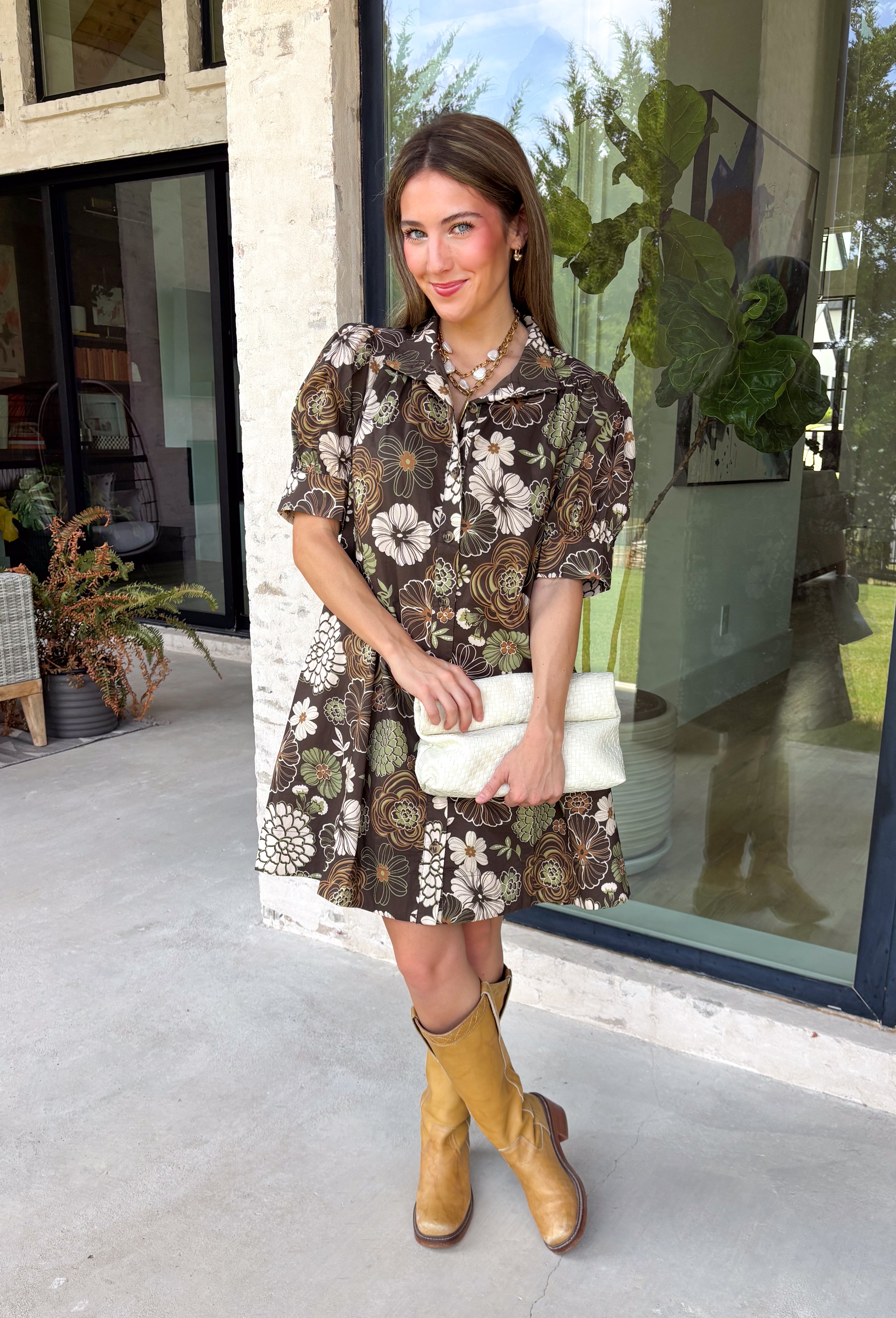 Warm autumn shades make this floral dress from Entro an easy pick for all your fall plans. The rich brown background is paired with a neutral floral print, creating a seasonal look that works beautifully for family photos, brunch, church, and weekend gatherings. A classic shirt collar and button-front closure give it a put-together feel, while short puff sleeves add just the right amount of shape. Pleated detailing at the back brings an unexpected touch to the silhouette.