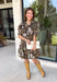 Warm autumn shades make this floral dress from Entro an easy pick for all your fall plans. The rich brown background is paired with a neutral floral print, creating a seasonal look that works beautifully for family photos, brunch, church, and weekend gatherings. A classic shirt collar and button-front closure give it a put-together feel, while short puff sleeves add just the right amount of shape. Pleated detailing at the back brings an unexpected touch to the silhouette.