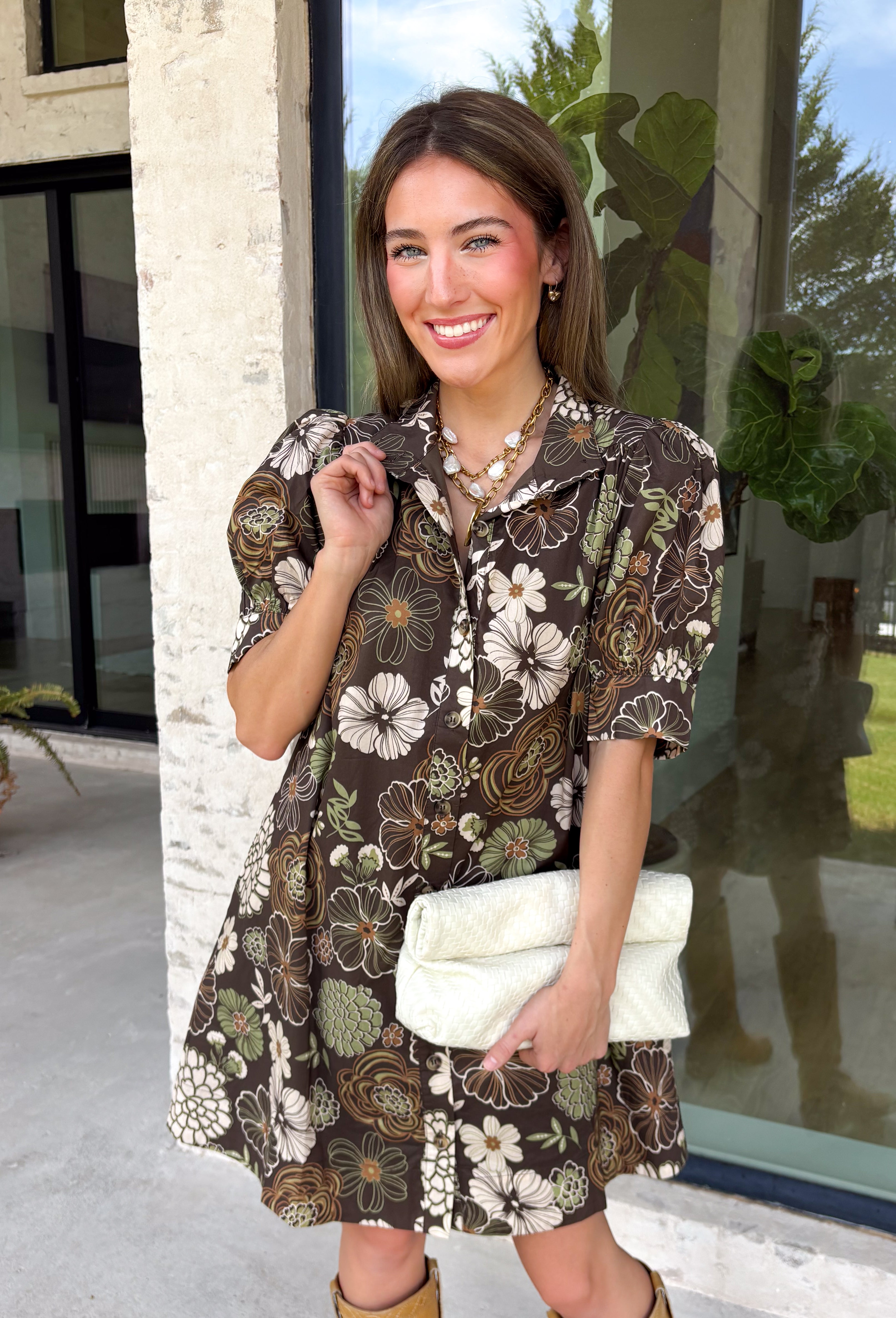 Warm autumn shades make this floral dress from Entro an easy pick for all your fall plans. The rich brown background is paired with a neutral floral print, creating a seasonal look that works beautifully for family photos, brunch, church, and weekend gatherings. A classic shirt collar and button-front closure give it a put-together feel, while short puff sleeves add just the right amount of shape. Pleated detailing at the back brings an unexpected touch to the silhouette.
