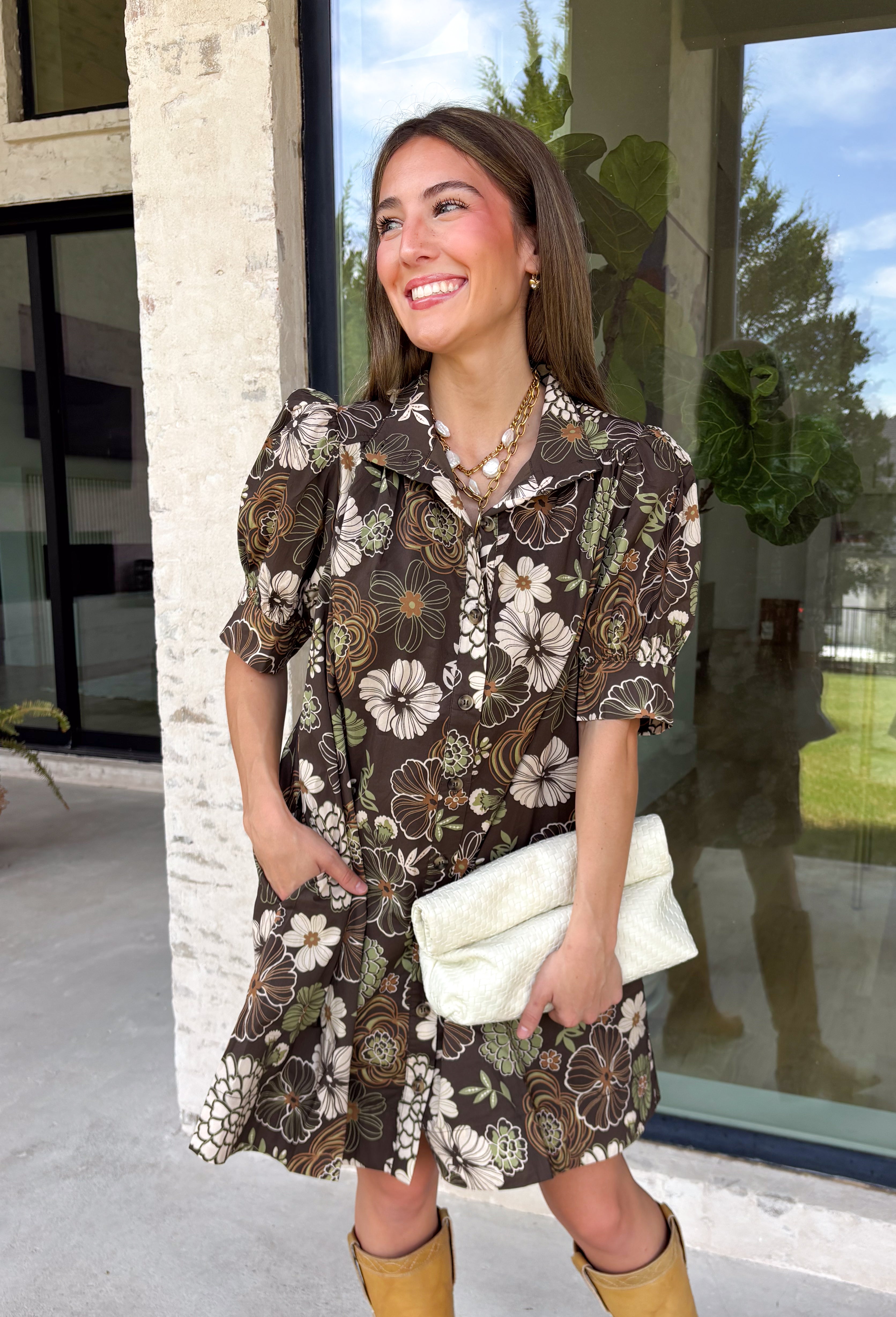 Warm autumn shades make this floral dress from Entro an easy pick for all your fall plans. The rich brown background is paired with a neutral floral print, creating a seasonal look that works beautifully for family photos, brunch, church, and weekend gatherings. A classic shirt collar and button-front closure give it a put-together feel, while short puff sleeves add just the right amount of shape. Pleated detailing at the back brings an unexpected touch to the silhouette.