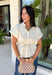 A timeless neutral top is one of the best investments for your fall wardrobe! This off white cotton blouse combines classic details with a flattering silhouette you'll love wearing on repeat. The collared neckline and button front create a polished look, while the elastic drawstring waist cinches just right for a feminine shape. Finished with a peplum hem and cap sleeves, it's the perfect blend of comfortable and elevated. 