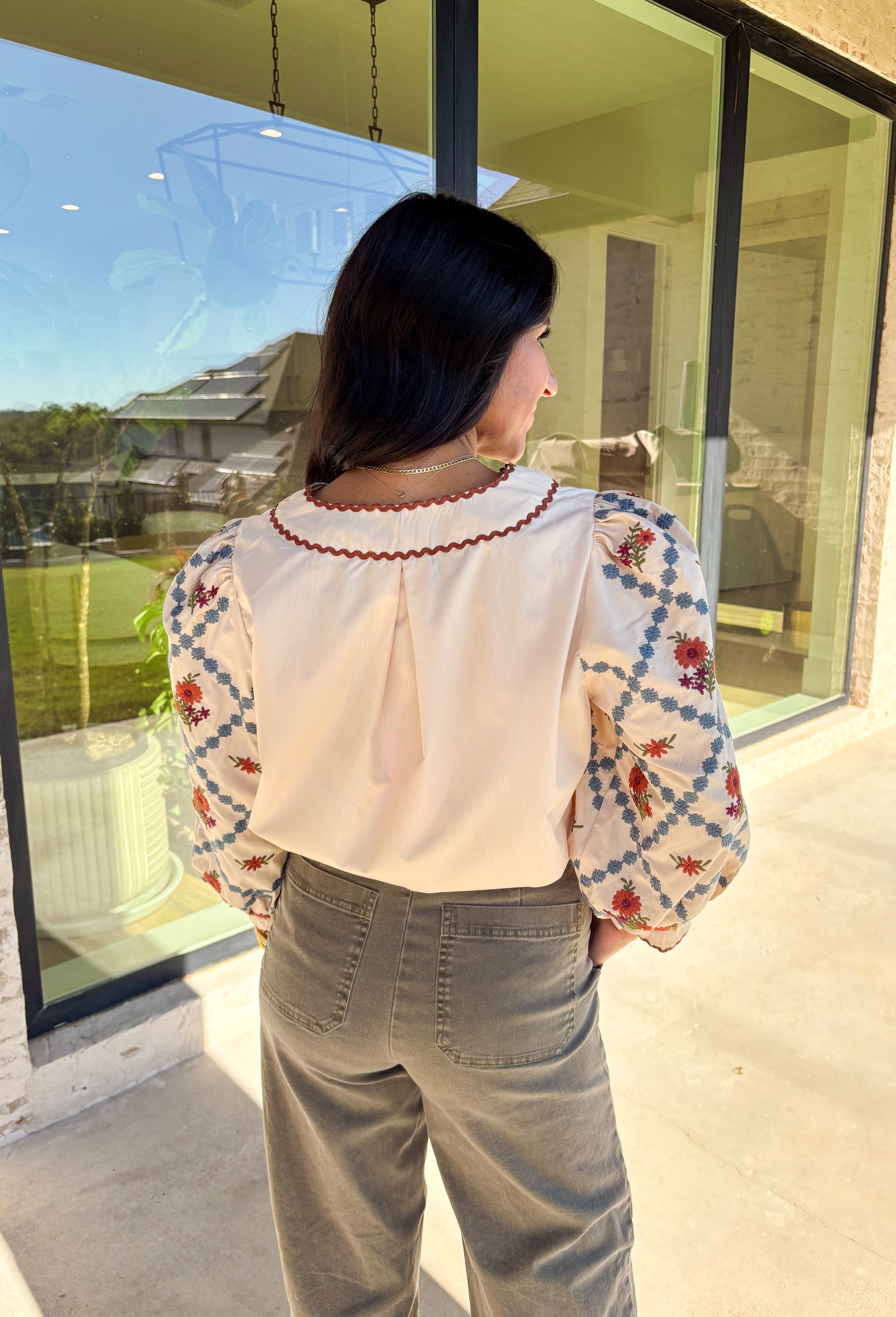 This ecru long sleeve top by Entro brings an elegant touch to your fall wardrobe with its beautifully embroidered floral sleeves. Detailed in shades of burgundy, rust, blue, and green, the embroidery stands out perfectly against the soft neutral base. The contrast scallop trim neckline adds a sweet finishing touch, giving this pullover top a timeless and feminine feel. Lightweight and easy to style, it’s a lovely go-to piece for both casual days and dressed-up outings.