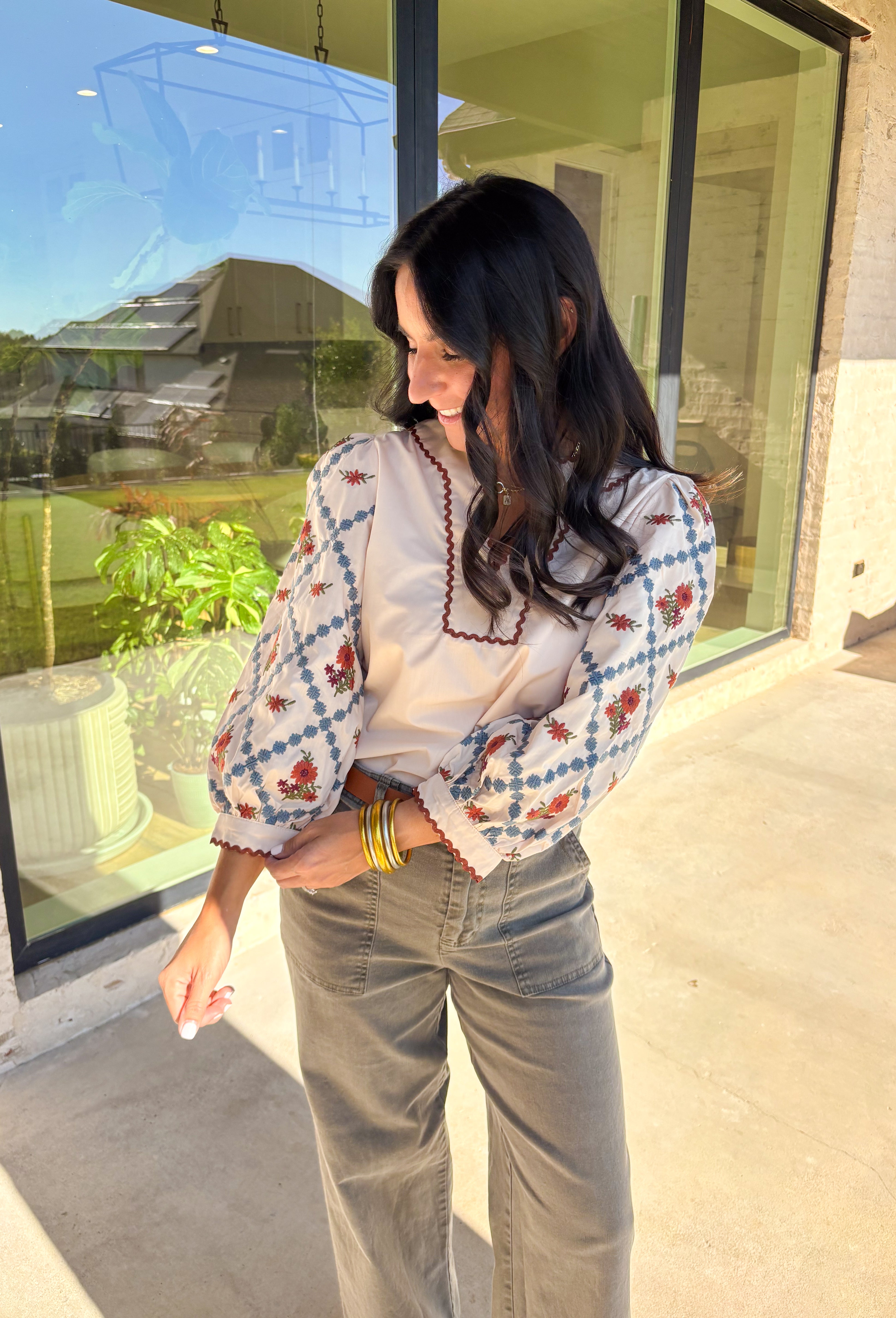 This ecru long sleeve top by Entro brings an elegant touch to your fall wardrobe with its beautifully embroidered floral sleeves. Detailed in shades of burgundy, rust, blue, and green, the embroidery stands out perfectly against the soft neutral base. The contrast scallop trim neckline adds a sweet finishing touch, giving this pullover top a timeless and feminine feel. Lightweight and easy to style, it’s a lovely go-to piece for both casual days and dressed-up outings.