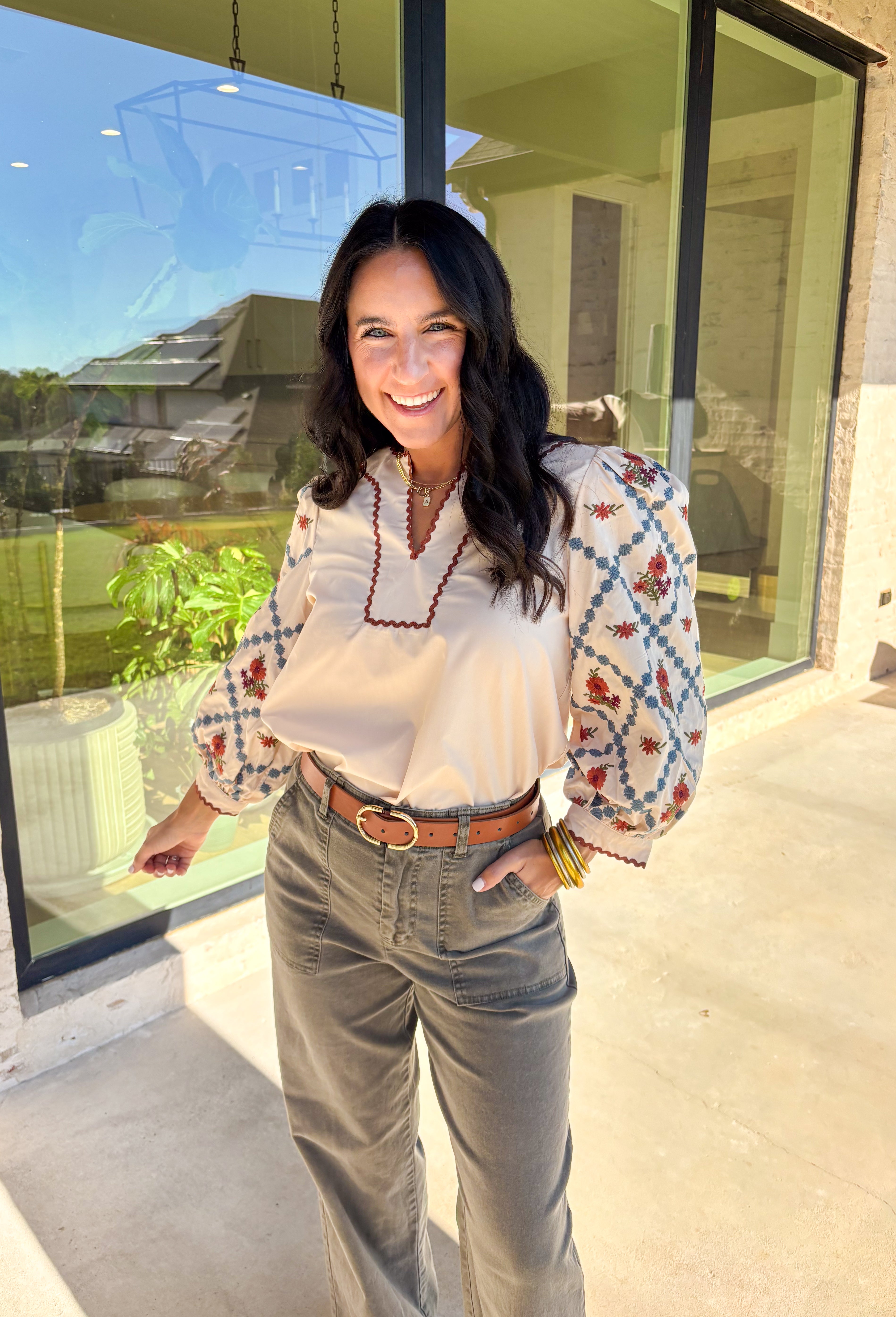 This ecru long sleeve top by Entro brings an elegant touch to your fall wardrobe with its beautifully embroidered floral sleeves. Detailed in shades of burgundy, rust, blue, and green, the embroidery stands out perfectly against the soft neutral base. The contrast scallop trim neckline adds a sweet finishing touch, giving this pullover top a timeless and feminine feel. Lightweight and easy to style, it’s a lovely go-to piece for both casual days and dressed-up outings.