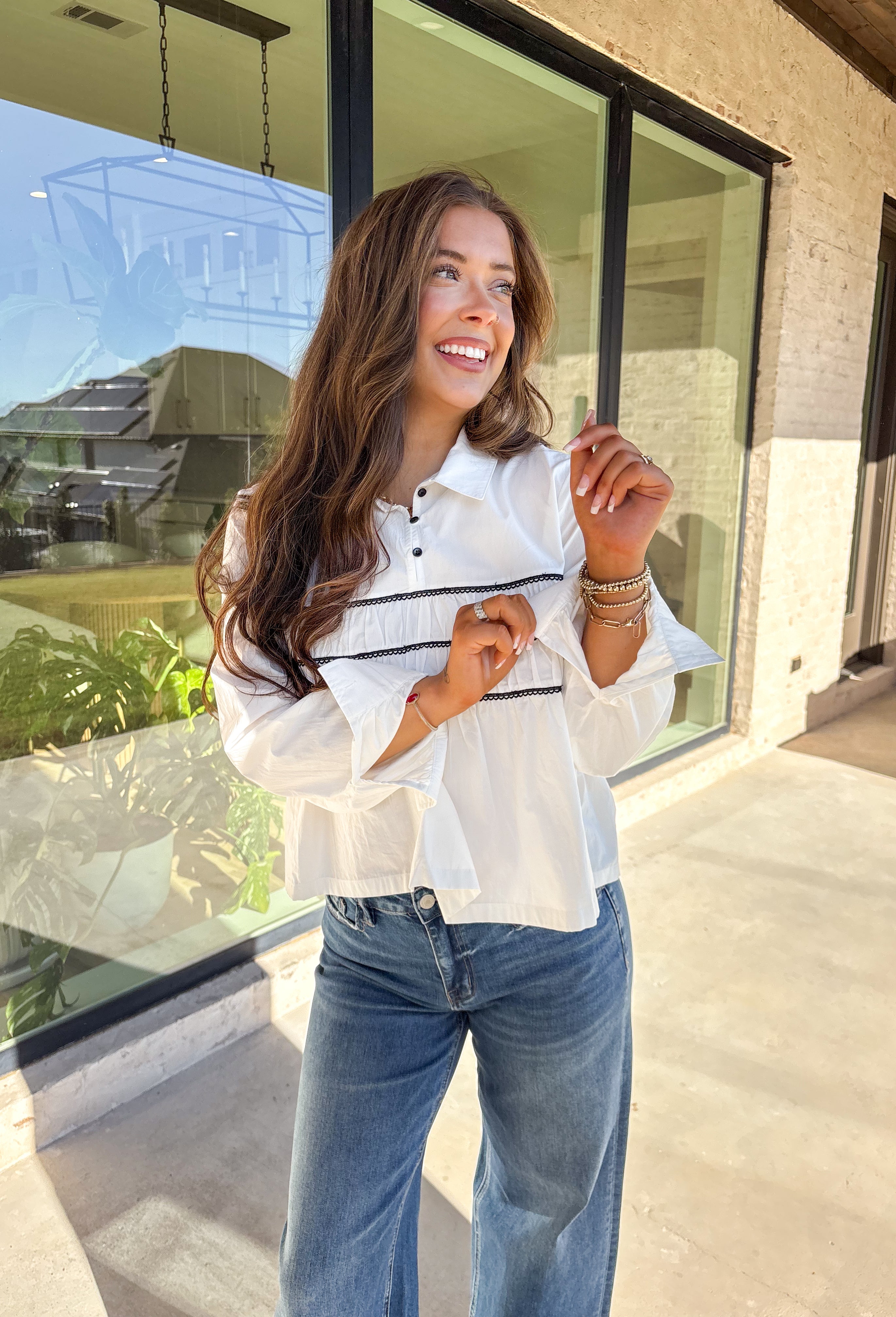 A polished essential with a playful twist—this white long sleeve top is designed with bold black scalloped trim running across the front and around the back for eye-catching contrast. The collared neckline and button detail give it a timeless look, while the crisp cotton fabric keeps it breathable and easy to wear. Perfect for layering or styling solo, this top transitions effortlessly from office days to cozy outings.