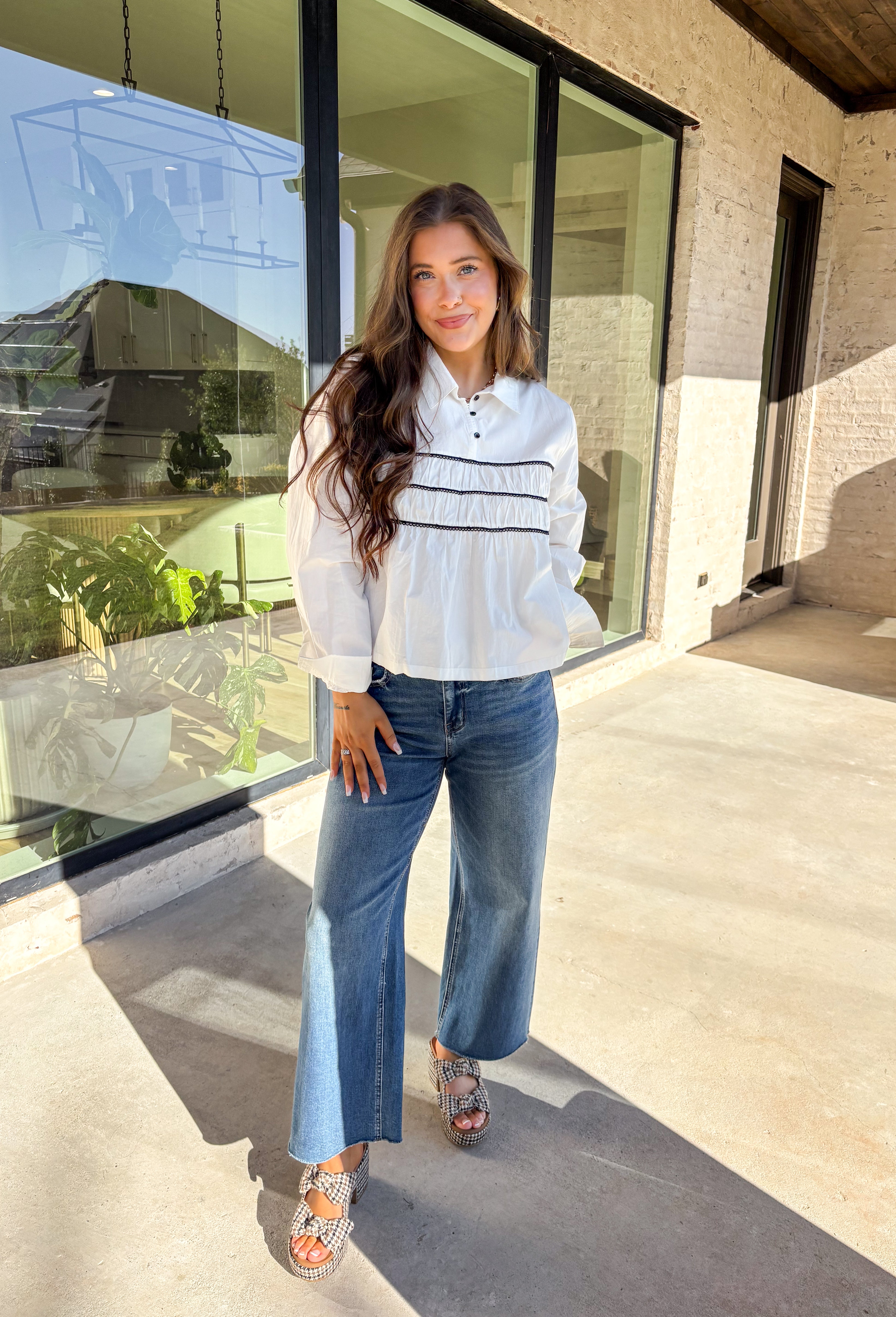 A polished essential with a playful twist—this white long sleeve top is designed with bold black scalloped trim running across the front and around the back for eye-catching contrast. The collared neckline and button detail give it a timeless look, while the crisp cotton fabric keeps it breathable and easy to wear. Perfect for layering or styling solo, this top transitions effortlessly from office days to cozy outings.