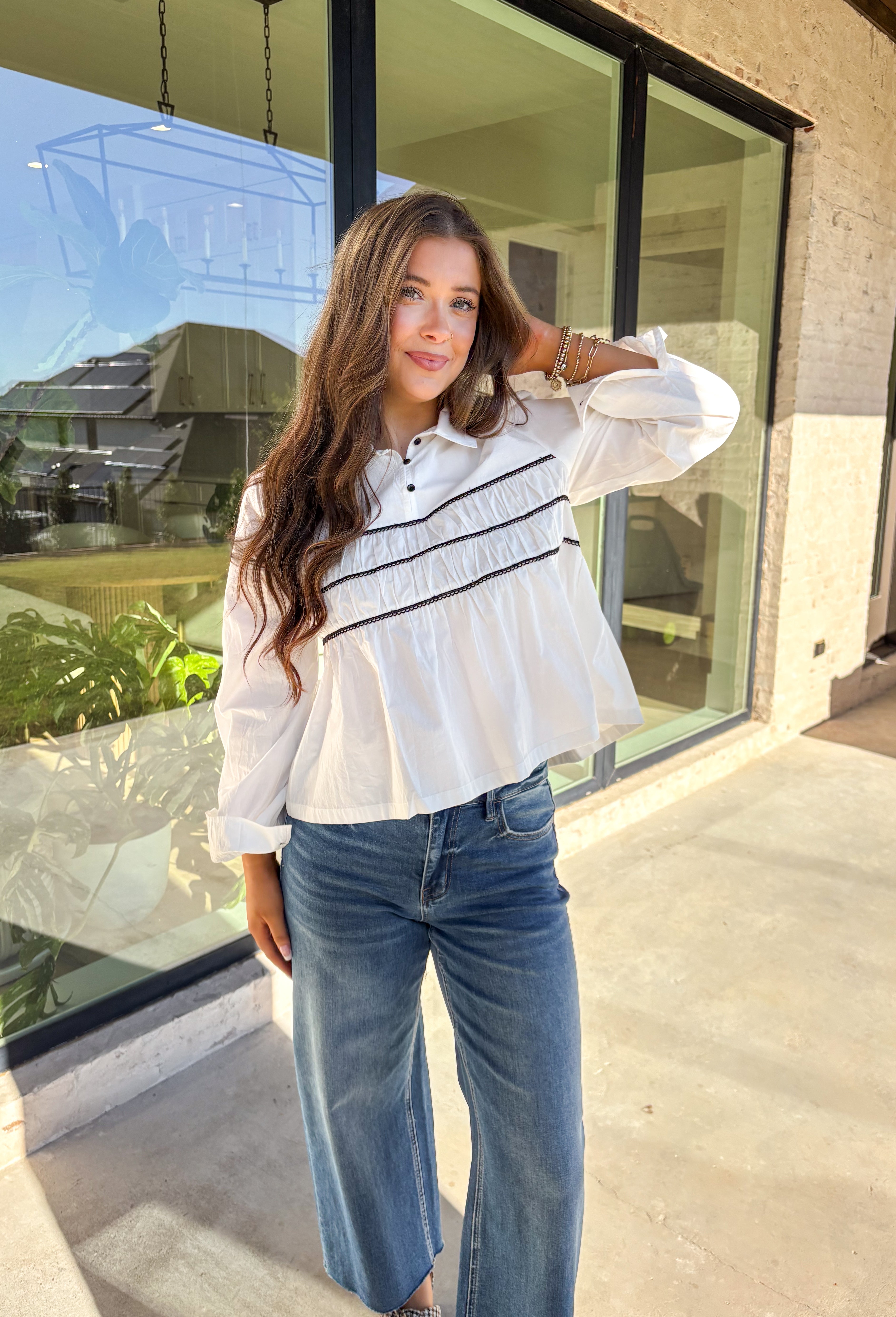 A polished essential with a playful twist—this white long sleeve top is designed with bold black scalloped trim running across the front and around the back for eye-catching contrast. The collared neckline and button detail give it a timeless look, while the crisp cotton fabric keeps it breathable and easy to wear. Perfect for layering or styling solo, this top transitions effortlessly from office days to cozy outings.