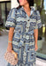 Bring effortless elegance to your wardrobe with this beautifully detailed dress from Entro. Designed with a soft light blue backdrop and an eye-catching abstract print in shades of navy, white, and cream, this timeless piece is perfect for everything from brunch dates to special gatherings. A subtle ruffle neckline adds a feminine touch, while the black buttons outlined in gold create an elevated, polished finish. 