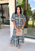 Bring effortless elegance to your wardrobe with this beautifully detailed dress from Entro. Designed with a soft light blue backdrop and an eye-catching abstract print in shades of navy, white, and cream, this timeless piece is perfect for everything from brunch dates to special gatherings. A subtle ruffle neckline adds a feminine touch, while the black buttons outlined in gold create an elevated, polished finish. 