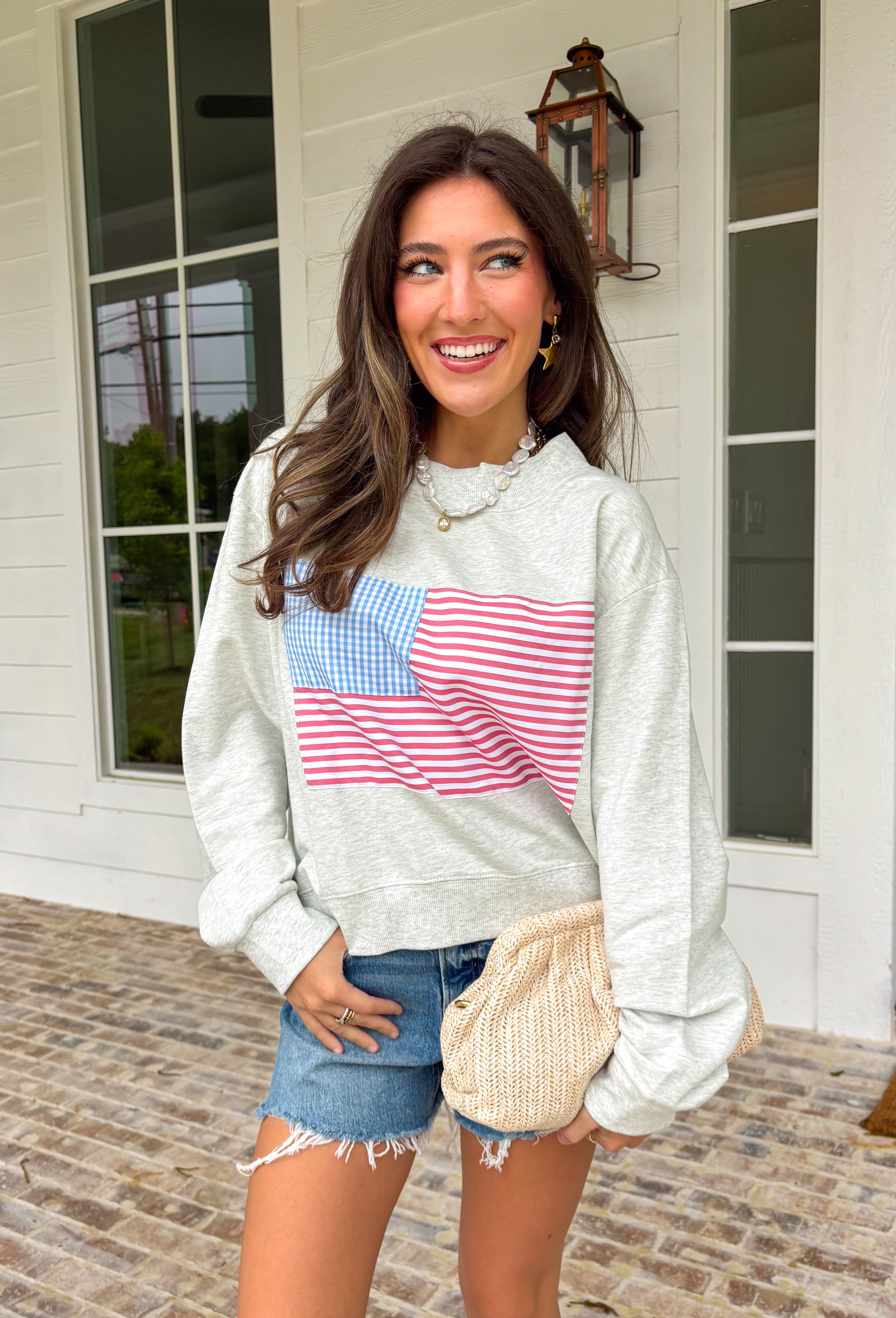 This heather grey pullover is the perfect cozy-meets-festive piece for your summer celebrations! Featuring red and white stripes with a blue and white gingham flag, it brings a fun, playful take on classic patriotic style. The mock neck adds a slightly elevated feel, while the soft cotton fabric keeps it comfortable for those breezy summer nights—think fireworks, lake evenings, or early morning coffee runs. It’s an easy throw-on piece that still feels festive and put together. 