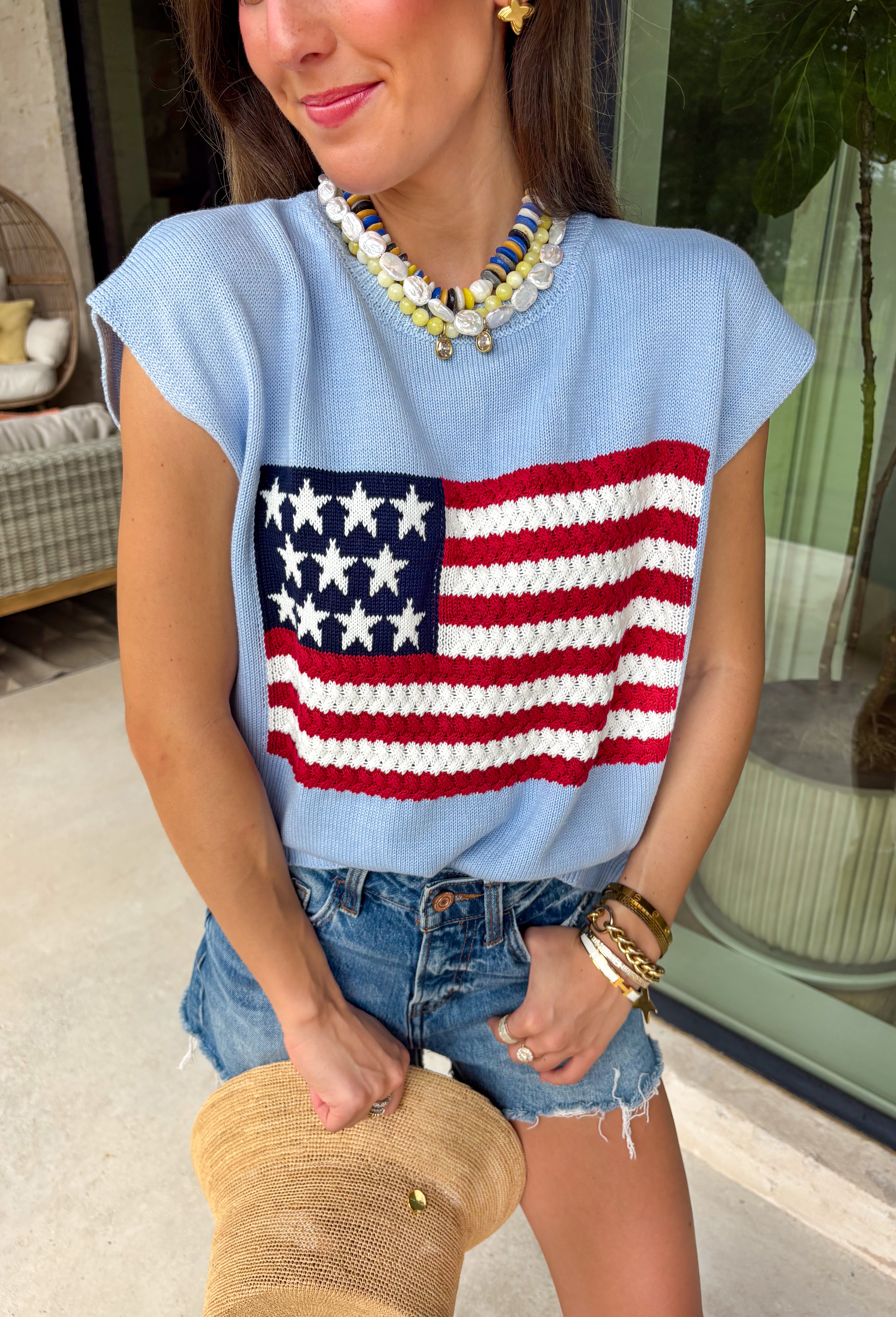 This light blue sweater top is the perfect way to celebrate summer in style! Featuring an American flag design on the front, it brings all the patriotic charm while still feeling classic and easy to wear. The lightweight knit construction makes it ideal for warm-weather celebrations, and the cap sleeves add a flattering, feminine touch. Whether you're heading to a backyard BBQ, a parade, a lake weekend, or fireworks with friends, this top is ready for all your 4th of July festivities. 