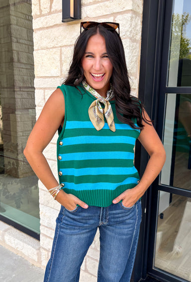 Classic stripes get a bold fall refresh with this cozy sleeveless sweater! Featuring a rich pine green knit with vibrant blue stripes, this sleeveless top is an easy way to add color to your seasonal wardrobe. Functional gold button closures along the sides add a unique, elevated touch, while the ribbed crew neckline and hem give it a timeless finish.