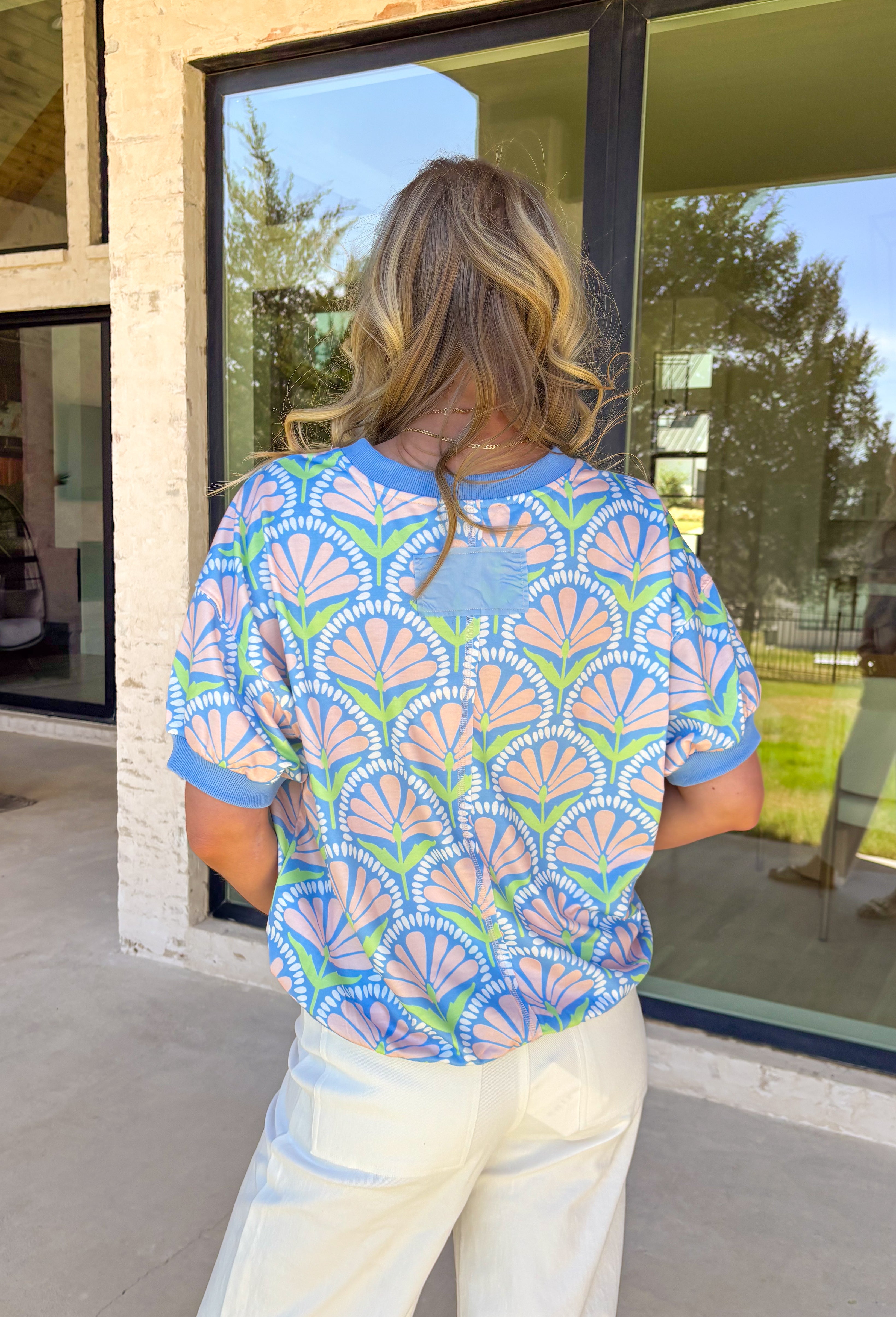 This short sleeve light blue top by Umgee is such a sweet and easy way to bring a little spring color into your everyday look. The floral print features soft pops of peach, white, and green for a fresh, pretty vibe that pairs perfectly with denim, white jeans, or even shorts once the weather warms up.The fabric has a light stretch that makes it easy to move in and super comfortable for all-day wear—whether you’re heading to work, running errands, or meeting friends for lunch. 