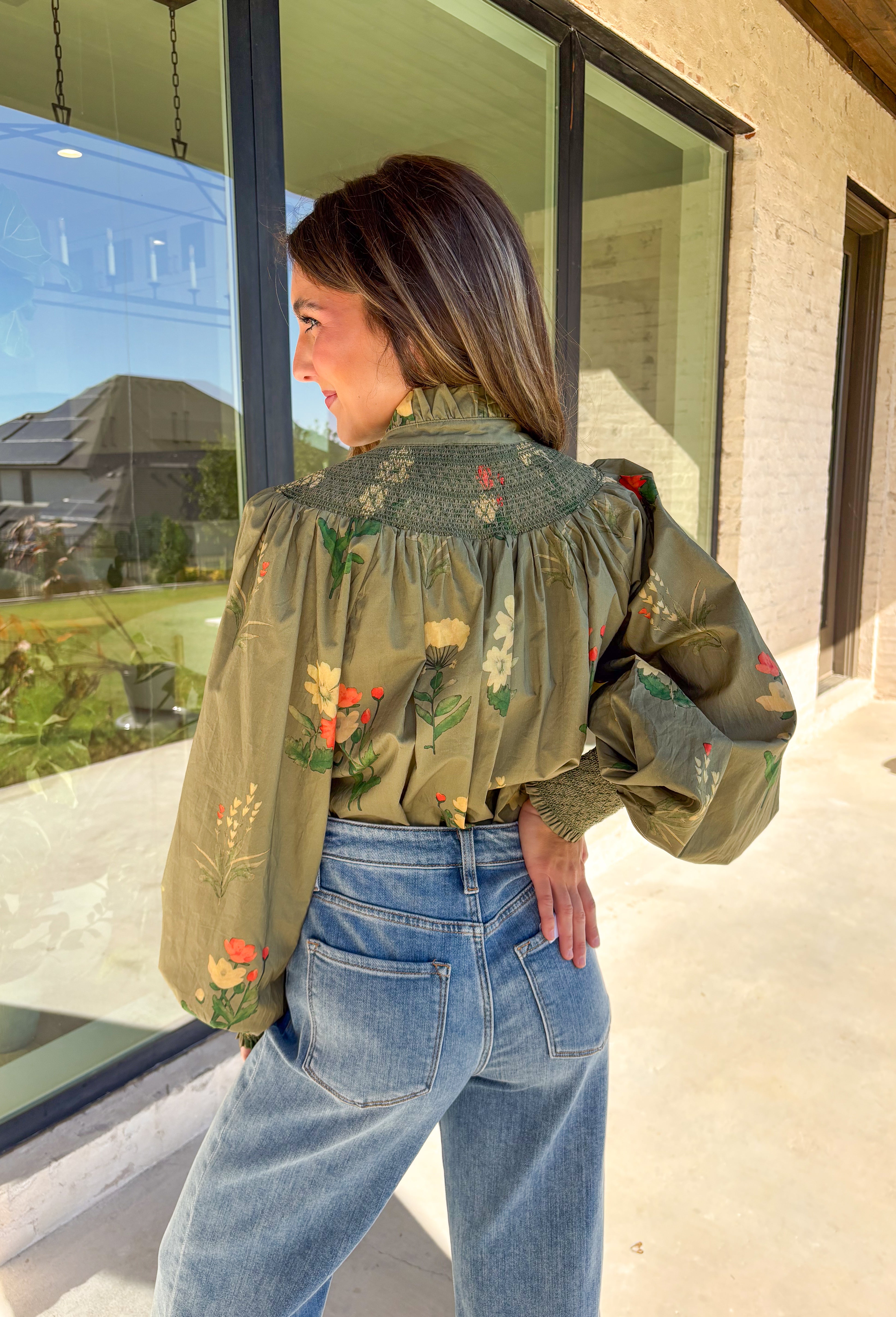 Romantic and timeless, this olive floral top by Entro is full of fall charm. The smocked yoke and ruffled mock neckline add a soft, feminine touch, while the button-front detail brings in classic appeal. Smocked cuffs create a subtle billowed sleeve effect, giving this piece a flattering silhouette. With shades of autumn florals throughout, it’s an easy choice for both casual days and dressier occasions.