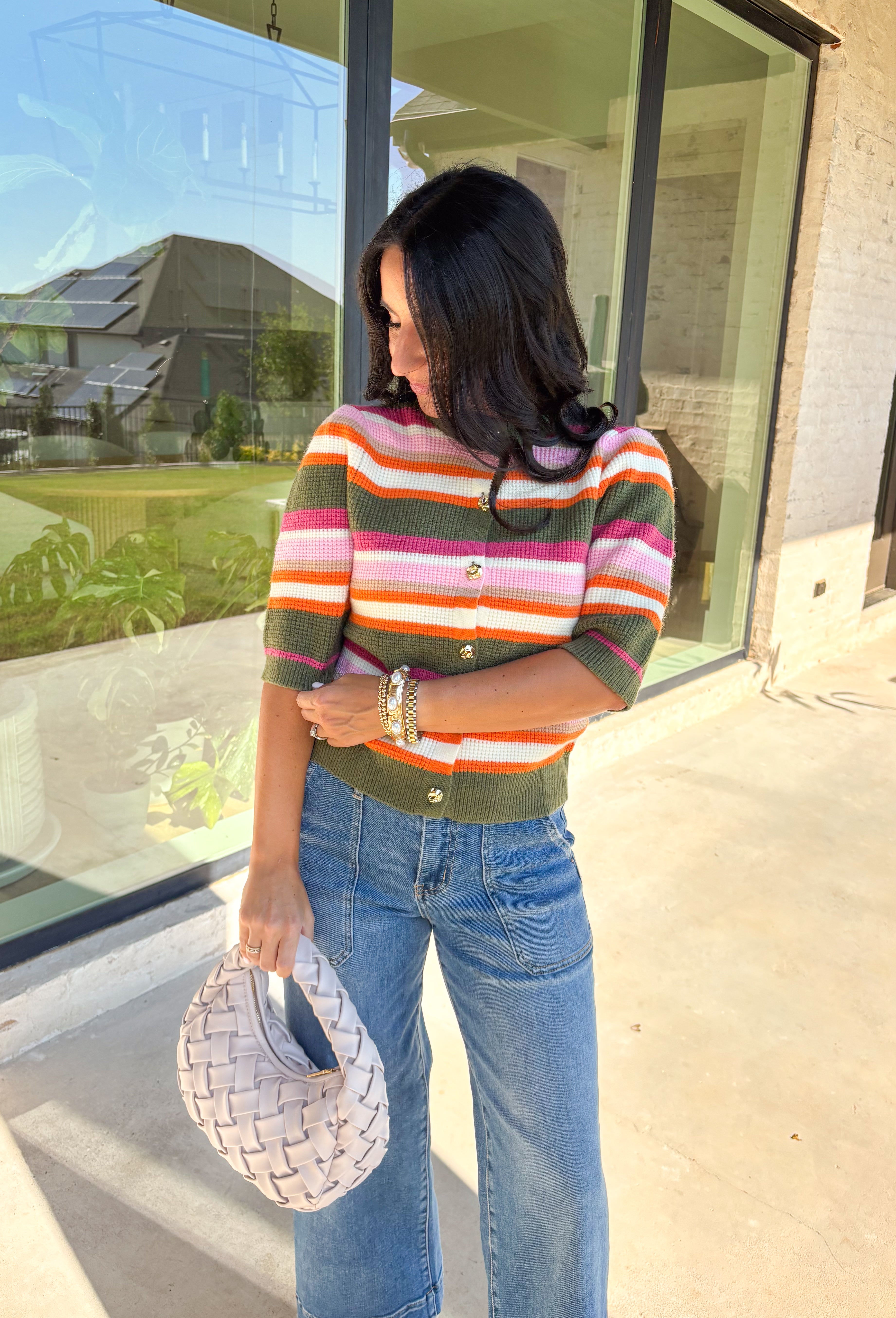 Add a playful pop to your fall wardrobe with this colorful knit cardigan. Designed in olive, shades of pink, white, tan, and orange, it’s a vibrant piece that feels both cozy and chic. The short sleeves make it easy to layer, while hammered gold buttons down the front add a polished finish. With its mix of warm tones and soft knit, this cardigan is a versatile piece you’ll find yourself reaching for all season long.