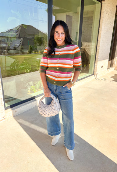 Add a playful pop to your fall wardrobe with this colorful knit cardigan. Designed in olive, shades of pink, white, tan, and orange, it’s a vibrant piece that feels both cozy and chic. The short sleeves make it easy to layer, while hammered gold buttons down the front add a polished finish. With its mix of warm tones and soft knit, this cardigan is a versatile piece you’ll find yourself reaching for all season long.