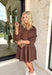 This brown textured dress is equal parts cozy and chic, making it a must-have for fall. Designed with a collared neckline and delicate ruffle trim, it brings a touch of femininity to its relaxed silhouette. The smocked balloon sleeves add volume and comfort, while the soft stretch fabric moves easily with you. Perfect for layering or styling on its own, this dress is ready to take you from weekday errands to weekend gatherings.