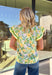 Fresh, cheerful, and full of spring charm, this off-white short sleeve top by Entro is a total sunshine piece. Featuring a green and yellow floral print with subtle pops of light pink, it brings the prettiest burst of color while still feeling soft and wearable. Cream and green trim down the front adds a fun contrast detail, and the green, yellow, and white trim on the sleeves ties everything together perfectly. Finished with a ruffle neckline for an extra feminine touch, this top is an easy pick for bright
