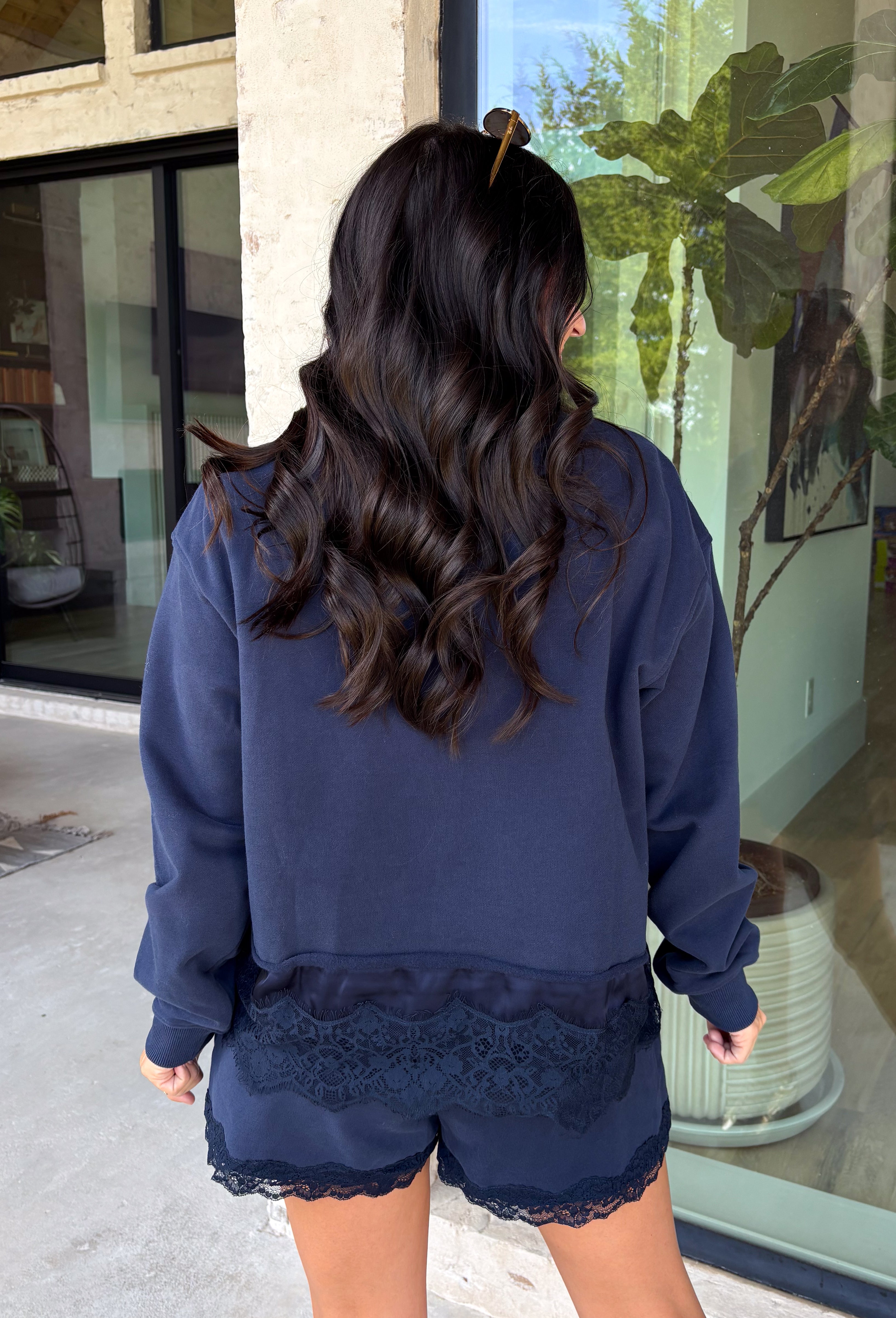 Cozy gets a pretty little upgrade with this navy sweatshirt from Sunday Edition. The classic long sleeve silhouette is finished with a lace hem, adding a feminine touch to an otherwise casual favorite. A soft fleece lining keeps it extra comfortable as chilly fall days start turning into winter weather. Pair it with the matching shorts for a cute coordinated set that’s perfect for relaxing, traveling, or casual weekend plans, or mix it into your closet with denim for an easy everyday outfit. 