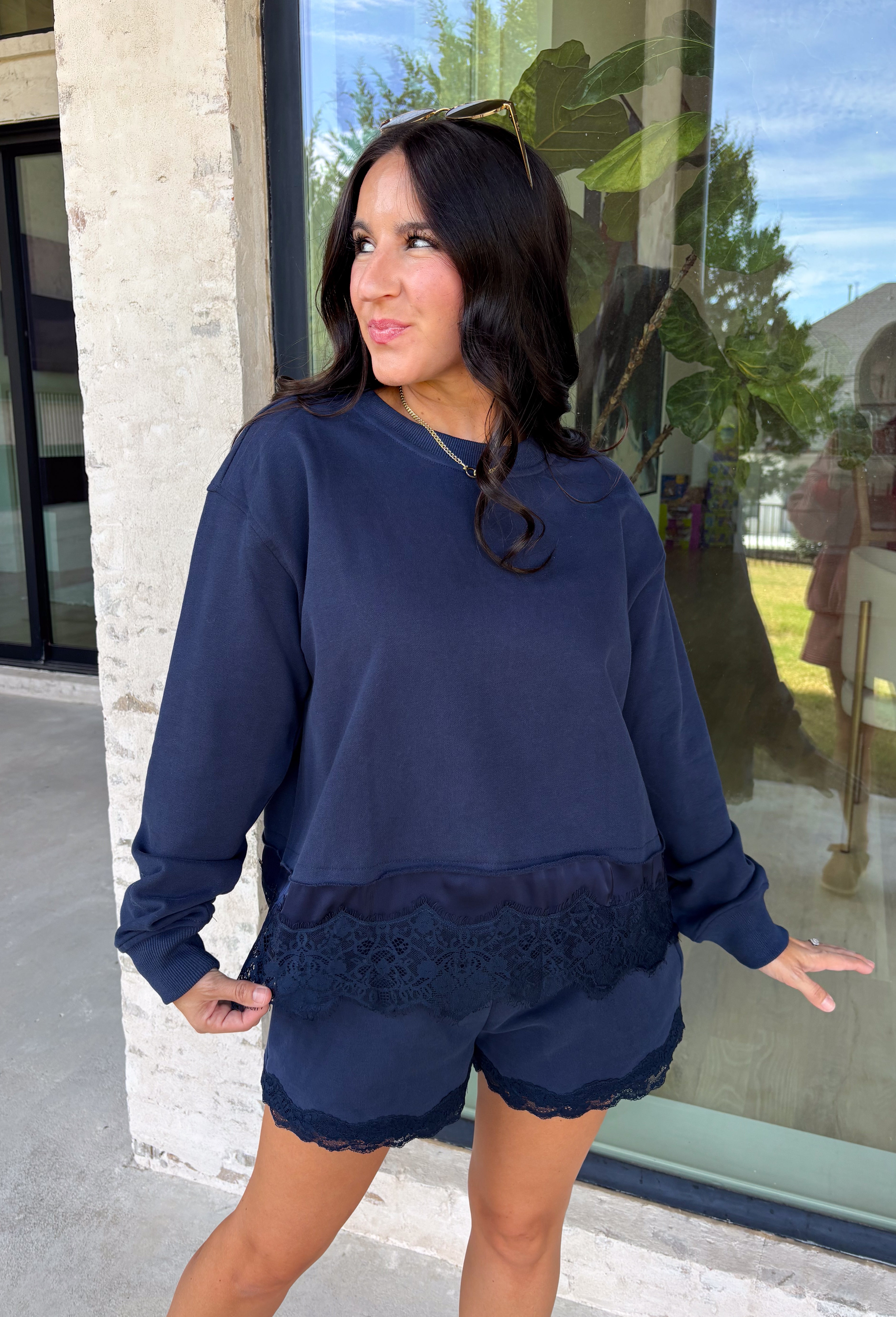 Cozy gets a pretty little upgrade with this navy sweatshirt from Sunday Edition. The classic long sleeve silhouette is finished with a lace hem, adding a feminine touch to an otherwise casual favorite. A soft fleece lining keeps it extra comfortable as chilly fall days start turning into winter weather. Pair it with the matching shorts for a cute coordinated set that’s perfect for relaxing, traveling, or casual weekend plans, or mix it into your closet with denim for an easy everyday outfit. 
