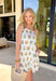 Bright, breezy, and full of spring charm, this sleeveless white dress is a total warm-weather favorite. The front features a gorgeous colorful embroidered print in shades of pink, green, yellow, blue, and brown, while the back stays solid white for a clean, classic contrast. Adjustable self-tie straps let you customize the fit, and the scalloped hem adds the sweetest finishing touch. 