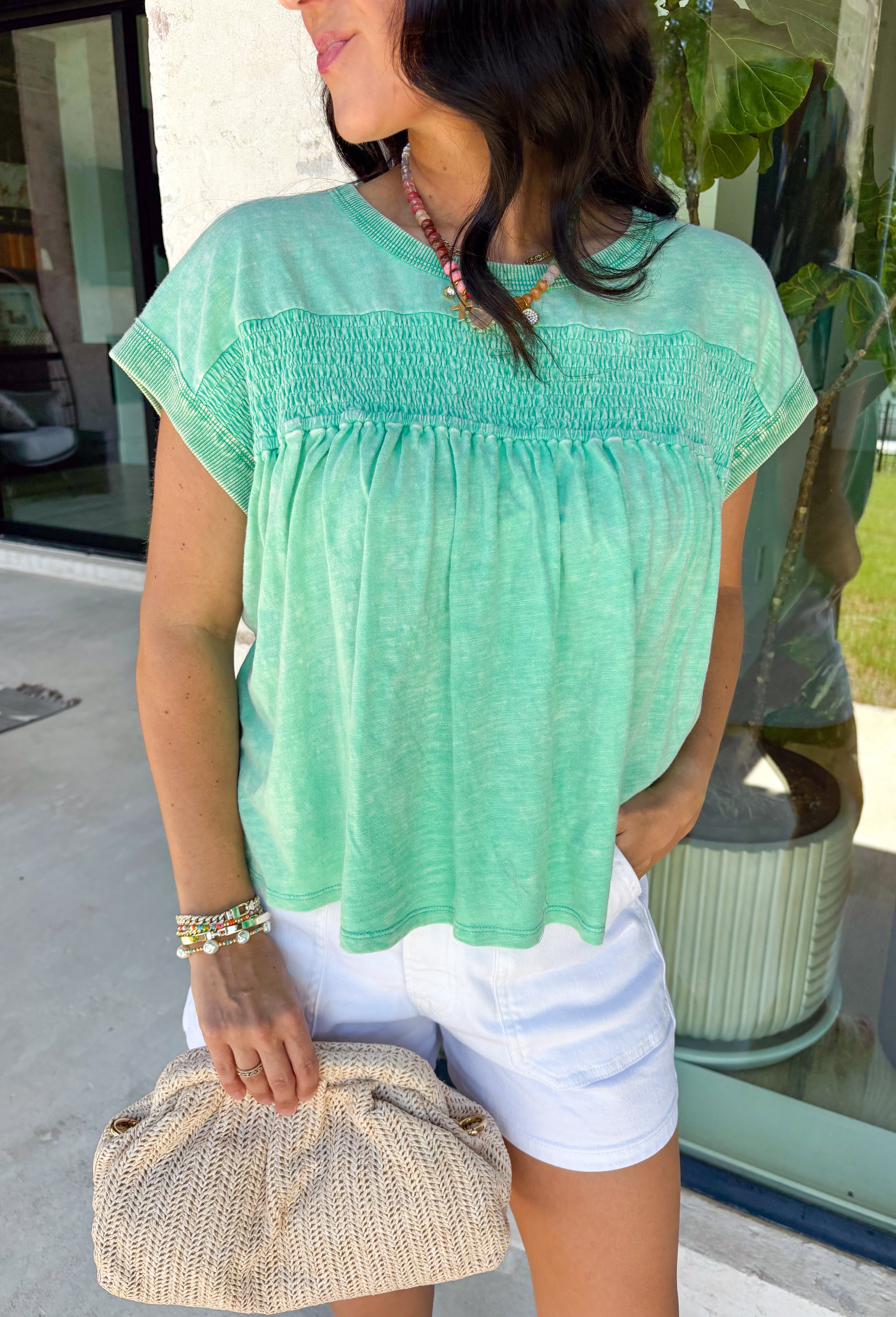 This green short sleeve top is the kind of easy, go-to piece you’ll reach for all summer long! The smocking detail across the front adds just the right amount of texture while creating a flattering, comfortable fit. Made from breathable 100% cotton, it’s lightweight and perfect for staying cool on warm days. It’s simple, versatile, and effortlessly put together—exactly what you want for busy days on the go. Pair it with denim shorts, white jeans, or a skirt for an easy everyday look. 