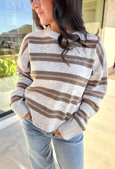This neutral striped sweater by Double Zero brings effortless comfort and style to your fall wardrobe. Featuring a flecked knit texture with brown stripes throughout, this mock neck pullover is as cozy as it is chic. The soft, medium-weight knit makes it perfect for layering or wearing solo on those crisp autumn days.
