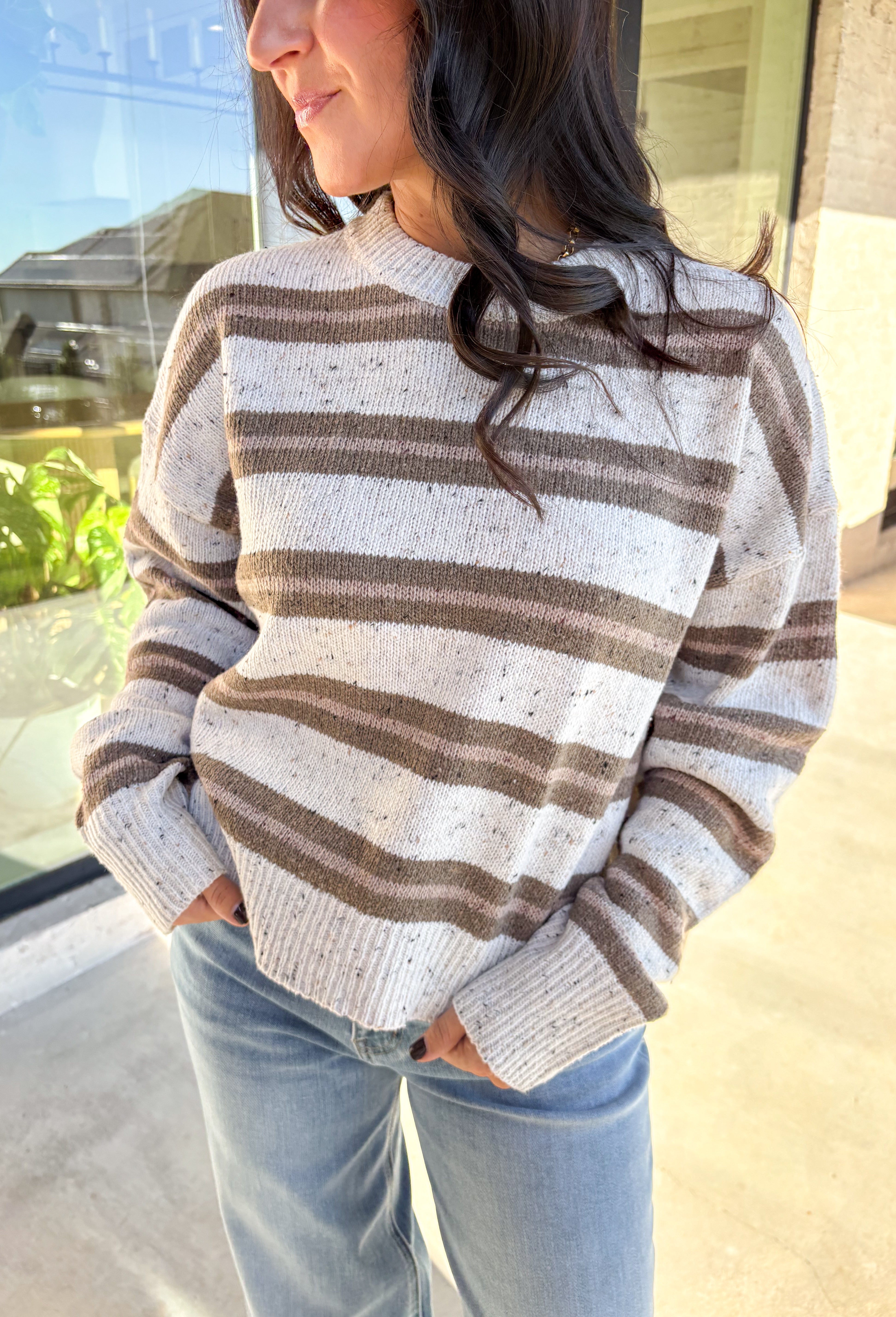 This neutral striped sweater by Double Zero brings effortless comfort and style to your fall wardrobe. Featuring a flecked knit texture with brown stripes throughout, this mock neck pullover is as cozy as it is chic. The soft, medium-weight knit makes it perfect for layering or wearing solo on those crisp autumn days.