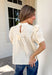 Soft, feminine, and effortlessly timeless, this beautiful ecru top is the kind of piece you'll treasure season after season! Crafted from breathable cotton, it features delicate lace detailing and chic pleating throughout for a look that's both romantic and refined. The puff sleeves add just the right amount of charm, while the keyhole button closure at the back provides a graceful finishing touch. 
