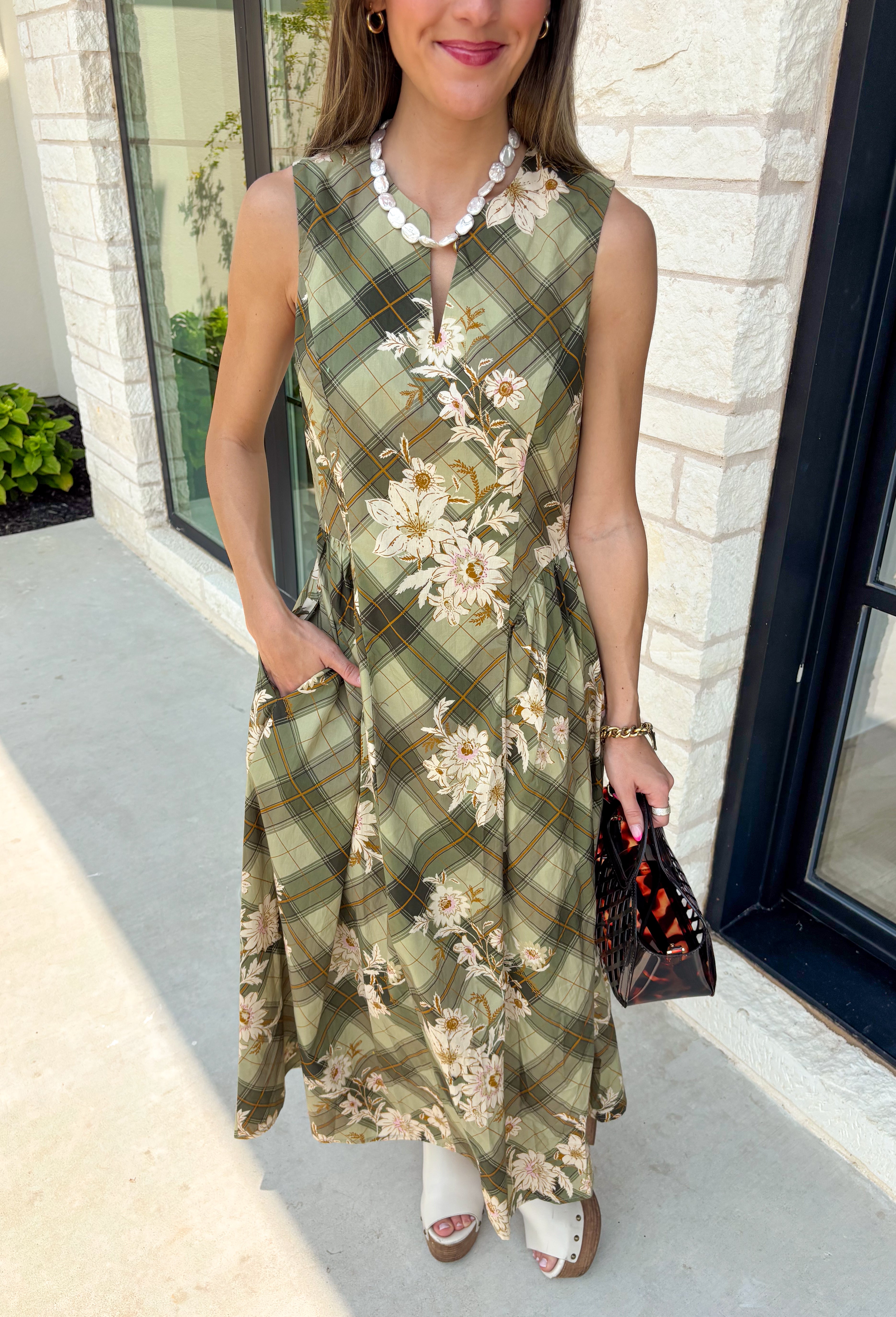 Classic plaid meets soft florals in this charming midi dress that's made for all your favorite fall occasions! Featuring an olive plaid backdrop with a neutral floral print, this cotton dress offers a unique blend of timeless patterns that feels effortlessly seasonal. The flattering v-neckline and sleeveless silhouette make it easy to wear on its own during warmer days or layered under a cardigan or denim jacket as the temperatures cool. 