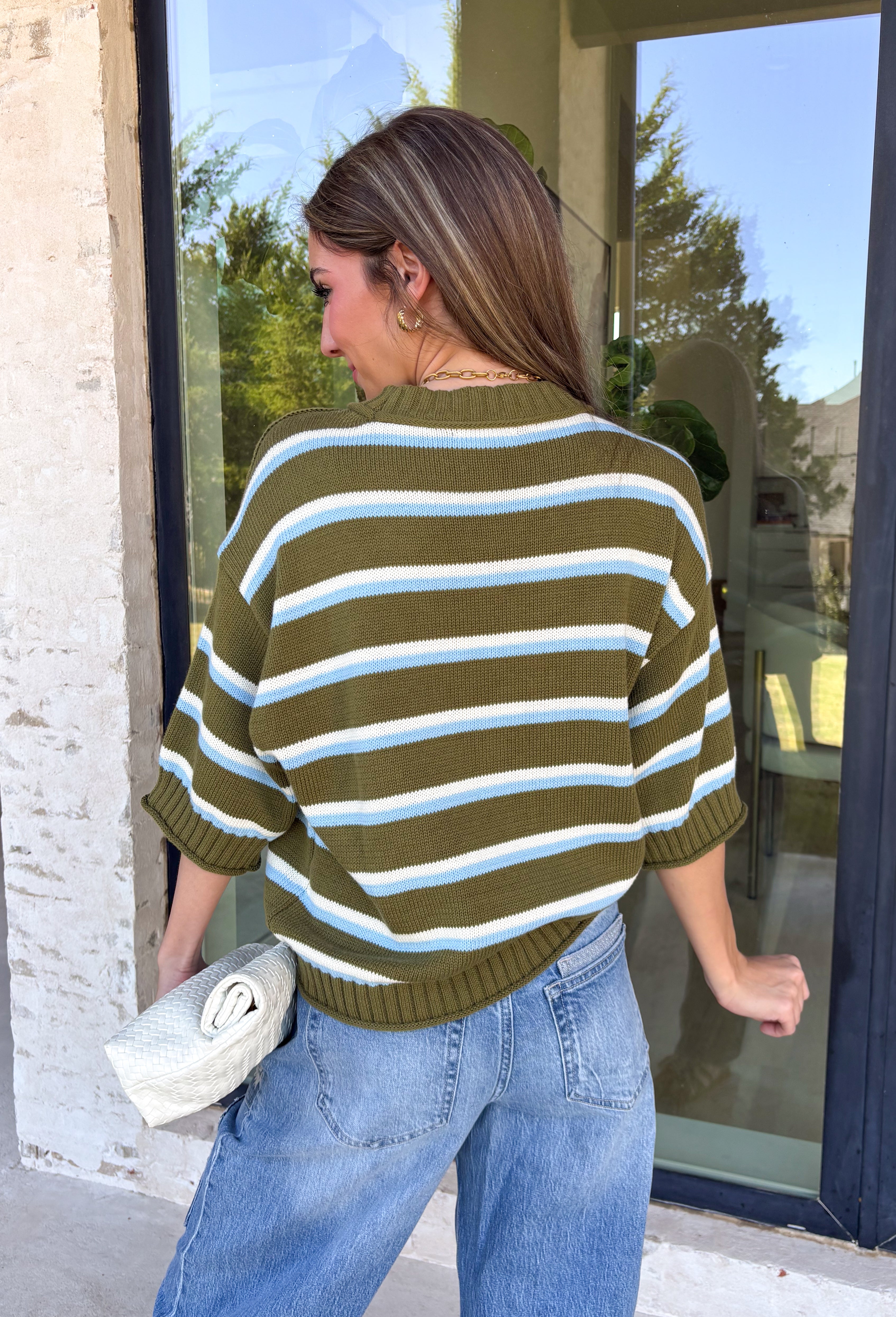 Fresh stripes and easy fall colors come together in this short sleeve sweater from Entro. The olive base is accented with off white and light blue stripes for a color combination that feels a little unexpected while still being easy to style. Made from 100% cotton, the knit has a comfortable feel that works especially well during those in-between fall days when it’s not quite cool enough for heavy layers. 