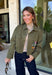 Make a statement everywhere you go with this stunning denim jacket from Veveret. Crafted in a rich olive denim, this standout layer features a breathtaking sheer embroidered floral design across the back, accented with shimmering sequins in shades of green, pink, orange, and brown. Coordinating floral sequin details on the front pockets tie the look together beautifully, while the classic collared neckline and button-front design keep it timeless. 