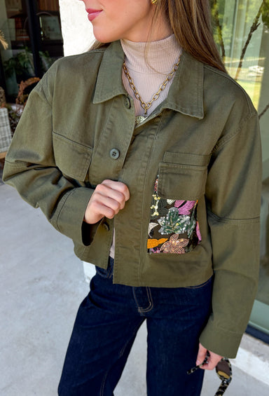 Make a statement everywhere you go with this stunning denim jacket from Veveret. Crafted in a rich olive denim, this standout layer features a breathtaking sheer embroidered floral design across the back, accented with shimmering sequins in shades of green, pink, orange, and brown. Coordinating floral sequin details on the front pockets tie the look together beautifully, while the classic collared neckline and button-front design keep it timeless. 