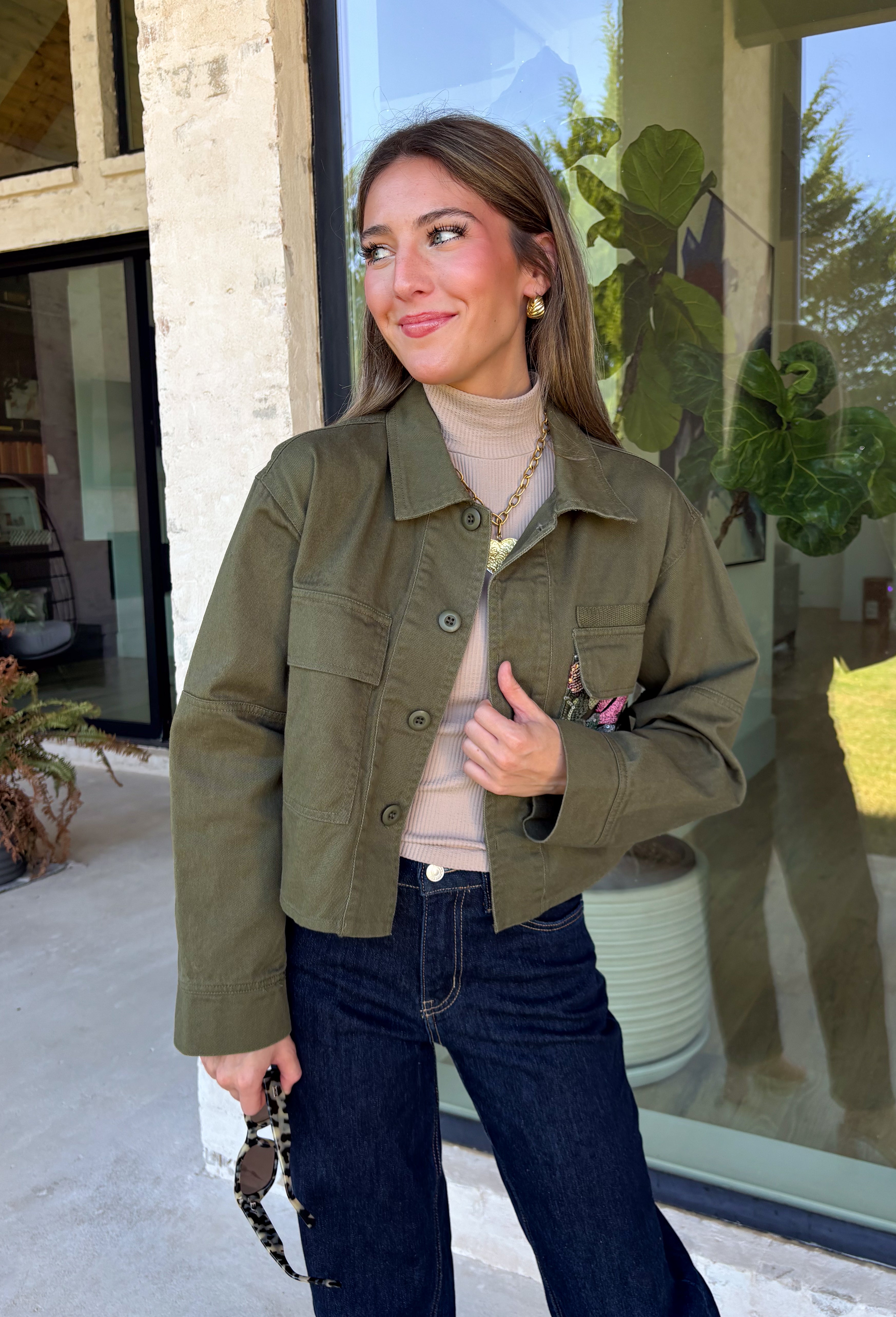 Make a statement everywhere you go with this stunning denim jacket from Veveret. Crafted in a rich olive denim, this standout layer features a breathtaking sheer embroidered floral design across the back, accented with shimmering sequins in shades of green, pink, orange, and brown. Coordinating floral sequin details on the front pockets tie the look together beautifully, while the classic collared neckline and button-front design keep it timeless. 