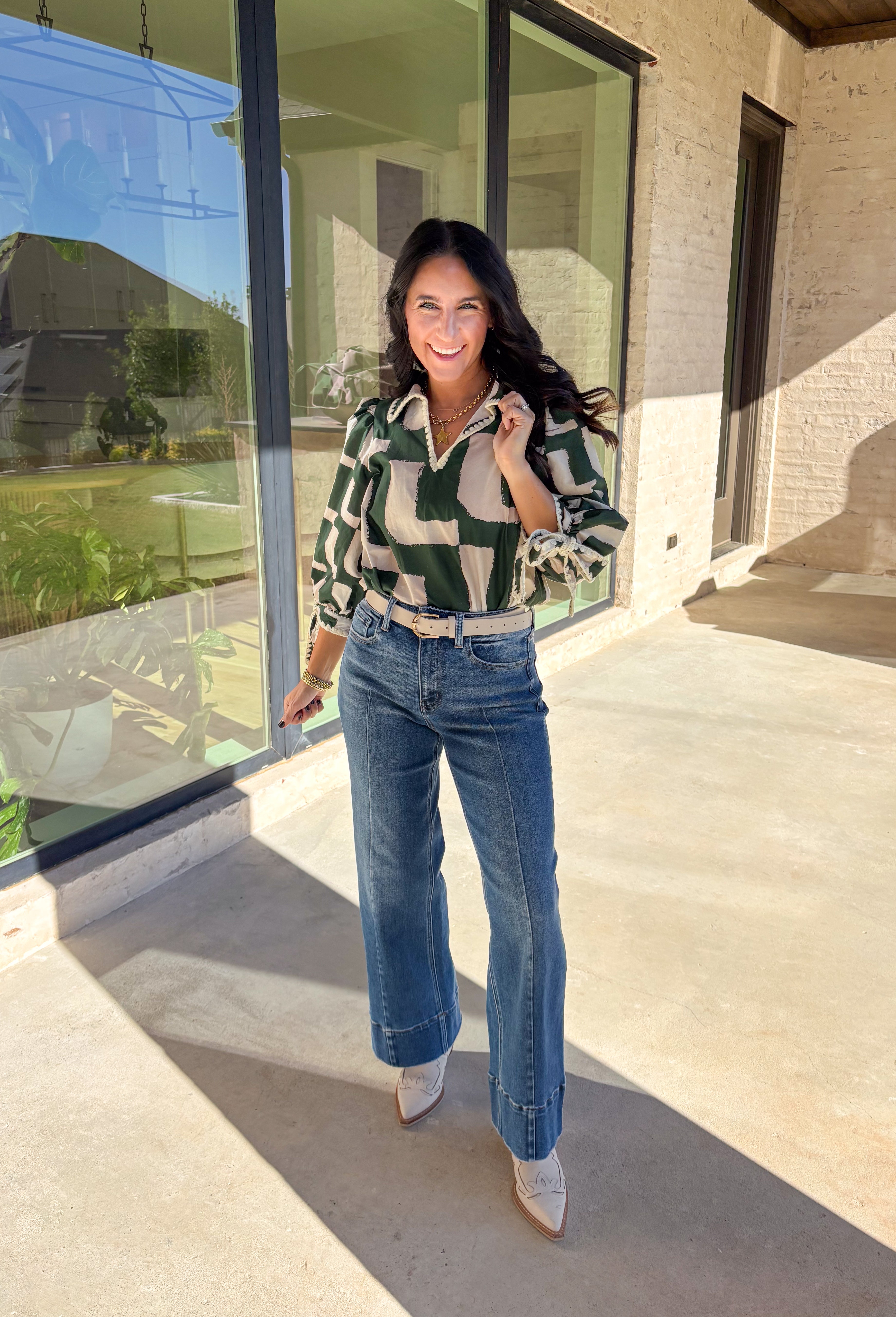 This hunter green top by Entro is full of personality and fall charm. Designed with an off-white abstract print, it features a split neckline with a collar and ¾ puff sleeves for a relaxed yet refined look. The scalloped trim and self-tie sleeve detail add a playful finish, giving this top a mix of polish and fun that’s easy to wear from workdays to weekends.