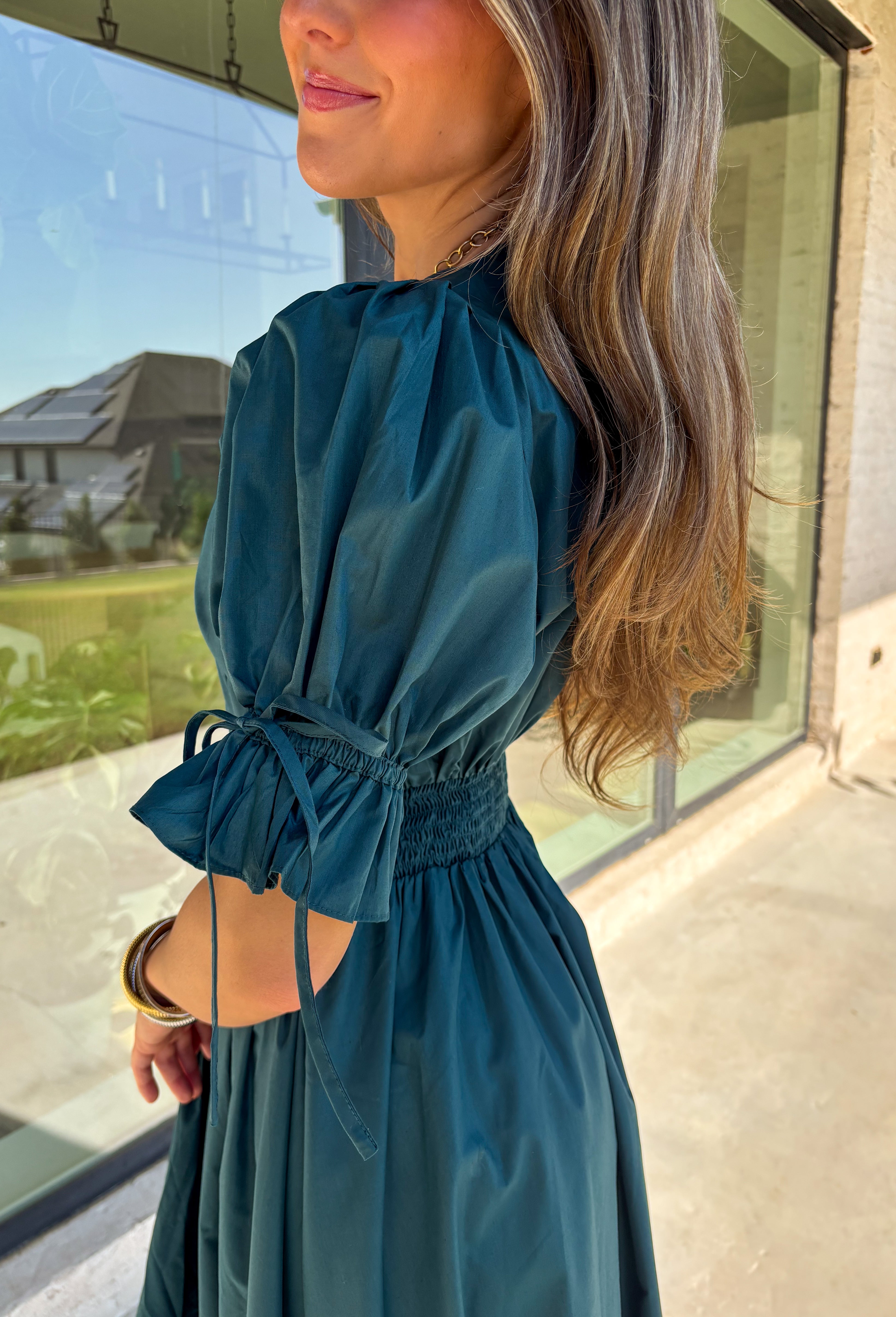 A statement piece with a touch of whimsy, this teal midi dress is designed to turn heads. Short puff sleeves and a flattering stitch-accent v-neckline pair beautifully with a defined waistband, while the embroidered skirt hem adds that extra bit of charm. The zipper front closure offers a modern twist, and the smocked waistband at the back ensures all-day comfort. This is perfect for any fall occasion!