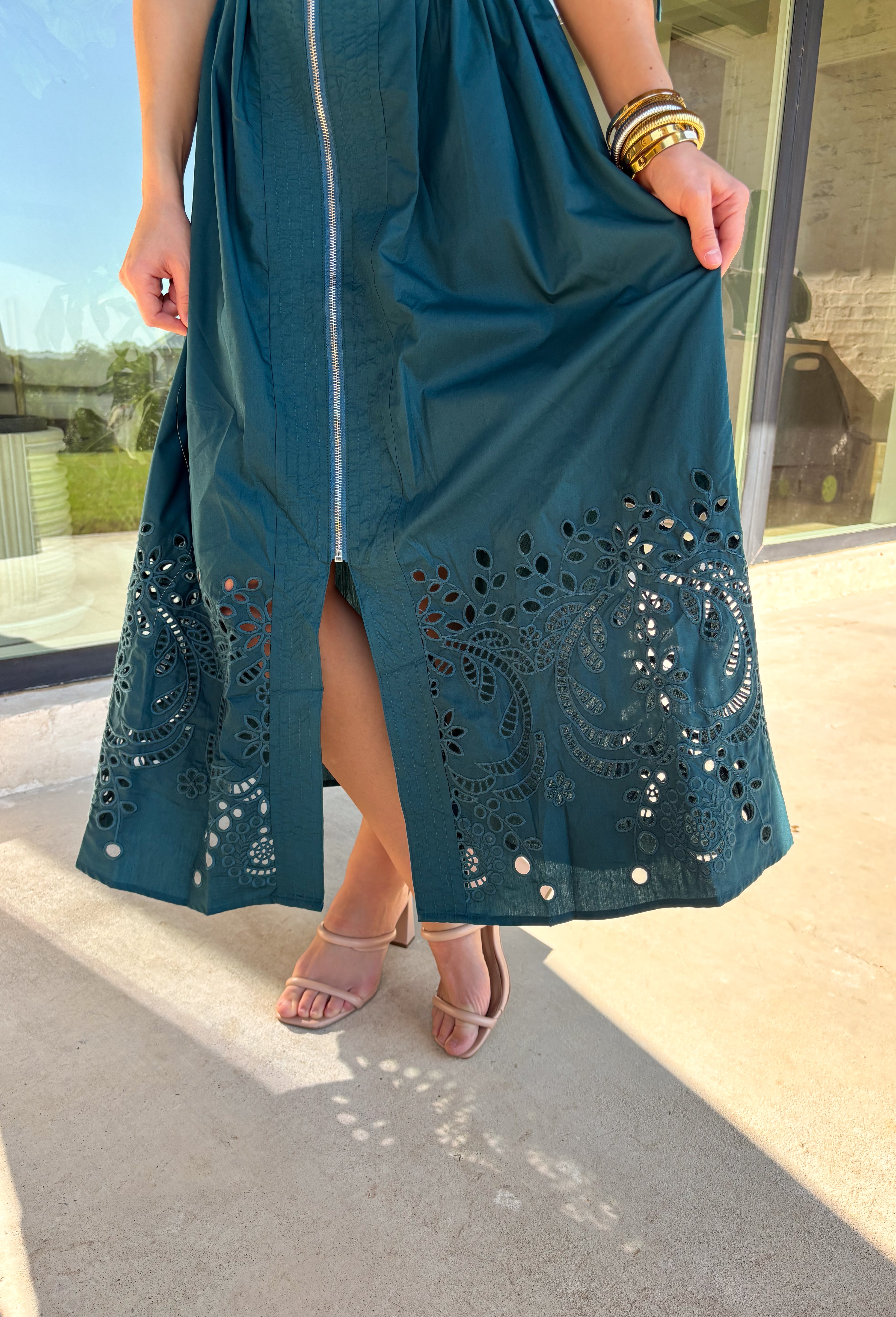 A statement piece with a touch of whimsy, this teal midi dress is designed to turn heads. Short puff sleeves and a flattering stitch-accent v-neckline pair beautifully with a defined waistband, while the embroidered skirt hem adds that extra bit of charm. The zipper front closure offers a modern twist, and the smocked waistband at the back ensures all-day comfort. This is perfect for any fall occasion!