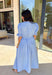 A statement piece with a touch of whimsy, this light blue midi dress is designed to turn heads. Short puff sleeves and a flattering stitch-accent v-neckline pair beautifully with a defined waistband, while the embroidered skirt hem adds that extra bit of charm. The zipper front closure offers a modern twist, and the smocked waistband at the back ensures all-day comfort. This is perfect for any spring occasion!