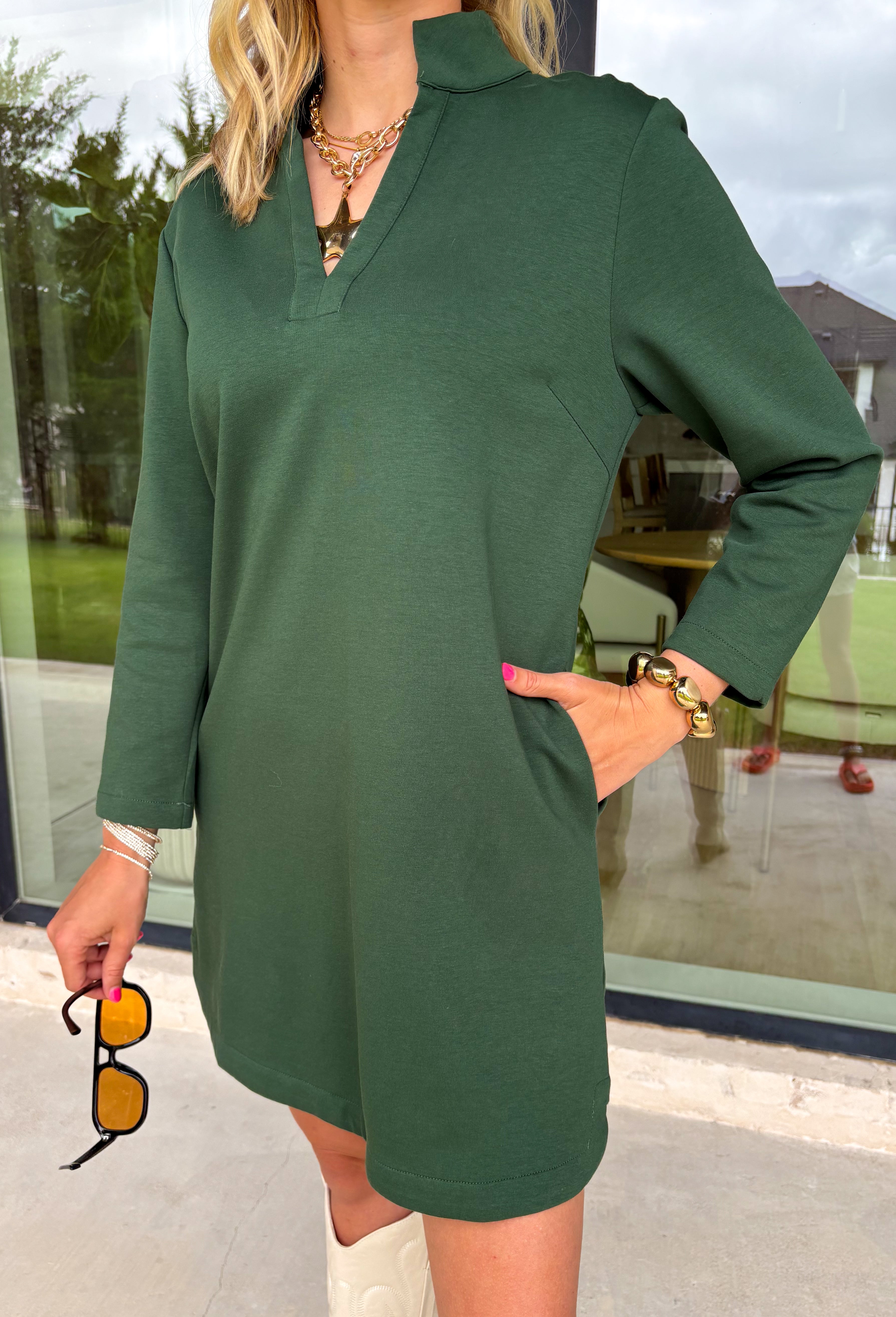 Simple, chic, and oh-so-flattering — this hunter green dress by Entro is a must-have for the season. Designed with a split v-neck and stand collar, it gives off an effortlessly polished vibe that can go from workday to weekend with ease. The soft stretch blend keeps it comfy, while the side pockets add a practical touch. Perfect on its own or layered with a jacket for those crisp fall days.
