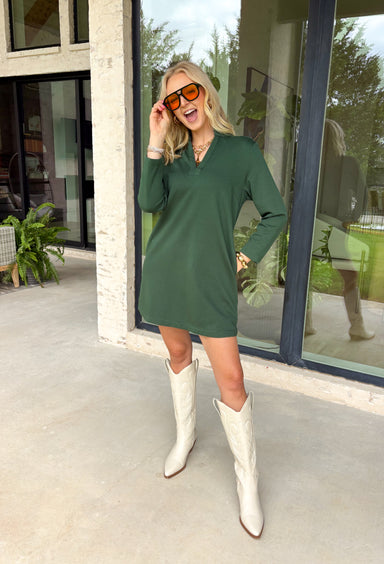 Simple, chic, and oh-so-flattering — this hunter green dress by Entro is a must-have for the season. Designed with a split v-neck and stand collar, it gives off an effortlessly polished vibe that can go from workday to weekend with ease. The soft stretch blend keeps it comfy, while the side pockets add a practical touch. Perfect on its own or layered with a jacket for those crisp fall days.