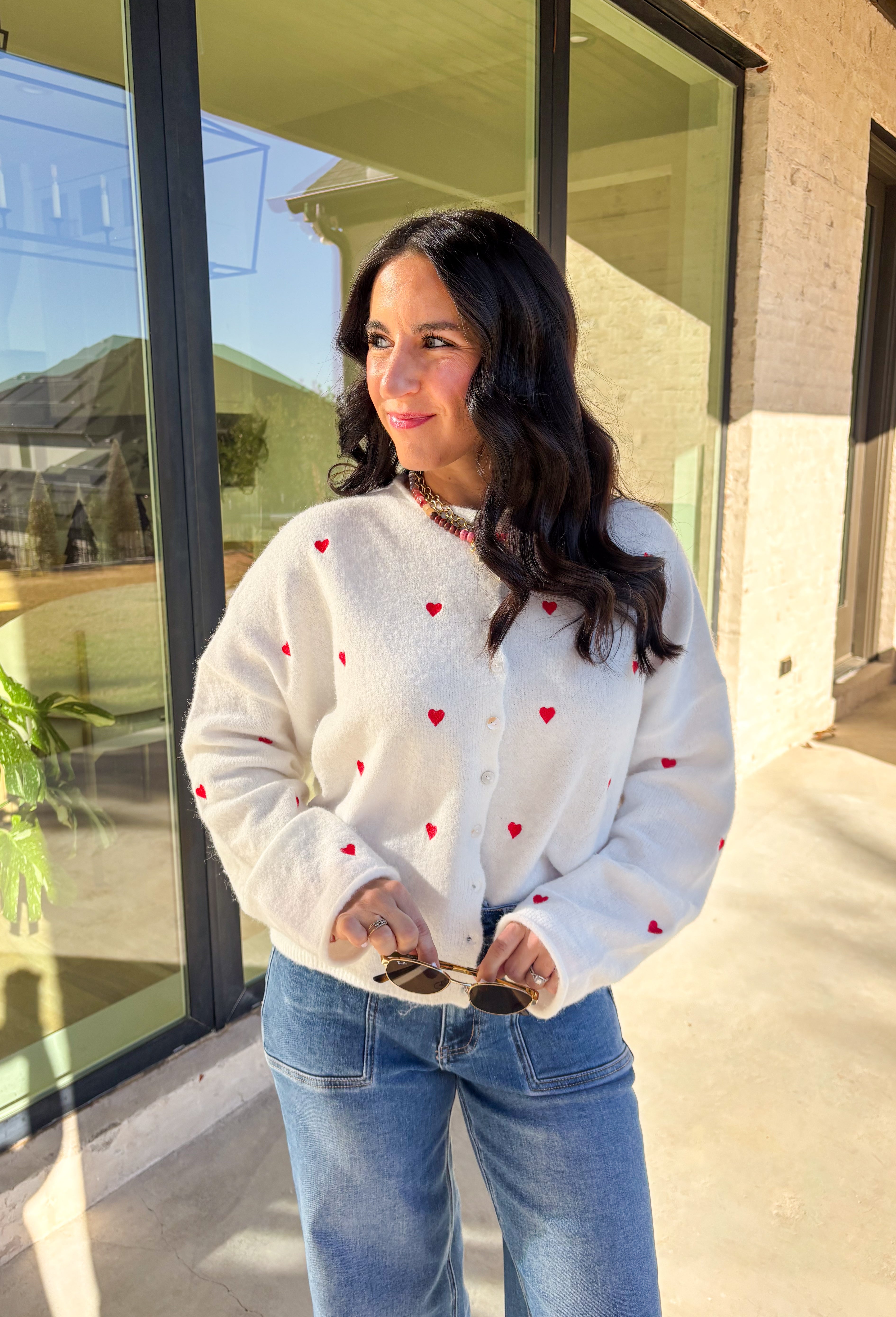 Add a little love to your look with this darling white button-down cardigan by Things Between. Featuring red embroidered hearts throughout and a scalloped trim along the front, this cozy knit is the perfect mix of cute and classic. Soft, feminine, and full of charm, it’s the perfect layer for Valentine’s Day and beyond.