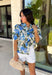 Fresh, feminine, and perfect for spring, this off-white button-down top by Entro is an easy standout. Featuring a blue floral print with pops of hunter green, it gives you the prettiest mix of color while still feeling classic and wearable. The ruffle neckline adds a sweet, polished touch, and puff sleeves bring that soft, feminine silhouette we love. Made from breathable cotton, this top is perfect for sunny days, brunch plans, and effortless spring outfits.