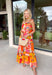 This orange sleeveless midi dress is pure sunshine in outfit form. Covered in a vibrant tropical print with pops of yellow, blue, green, and red, it instantly brings bold, vacation-ready energy to your wardrobe. The adjustable tie straps add a sweet, feminine touch while allowing for a customizable fit. Designed with a flowy tiered skirt and fully lined for easy wear, this dress is made for warm days, beach getaways, and sunny celebrations.