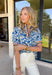 This short sleeve top by Voy is such a fun, fresh piece for spring! With its blue and white abstract floral print, it feels light, cheerful, and easy to style for everyday wear. The contrast trim along the neckline and sleeve cuffs adds the perfect pop of color in navy, white, green, and orange—giving it that extra little “wow” detail that makes it stand out from a basic top. Made from 100% cotton, it’s breathable and comfy for warm days, and it pairs effortlessly with everything.