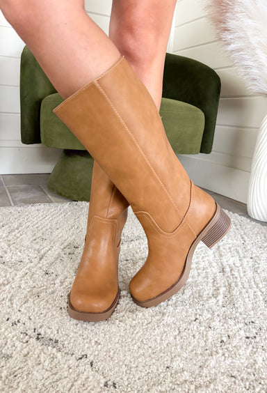 A timeless staple for every season, these tan faux leather riding boots by Soda bring classic charm with a modern edge. Designed with a rounded square toe and a stacked 2" block heel, they’re the perfect blend of comfort and polish. Whether you’re pairing them with denim, dresses, or skirts, these boots are a go-to style that will carry you through every occasion in effortless fashion.