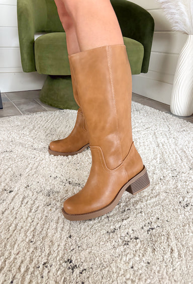 A timeless staple for every season, these tan faux leather riding boots by Soda bring classic charm with a modern edge. Designed with a rounded square toe and a stacked 2" block heel, they’re the perfect blend of comfort and polish. Whether you’re pairing them with denim, dresses, or skirts, these boots are a go-to style that will carry you through every occasion in effortless fashion.