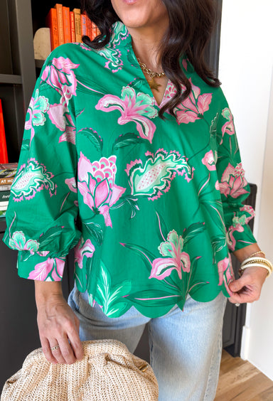 Fresh, colorful, and effortlessly pretty, this green long sleeve top by Entro is a perfect spring staple. Featuring a cheerful floral print in pink and white, it adds a bright pop of color while still feeling light and wearable. The v-neck band collar gives it a clean, polished look, while the scalloped hem adds a sweet, feminine finish. Buttoned cuffs complete the look, making this top easy to dress up or wear casually all season long.