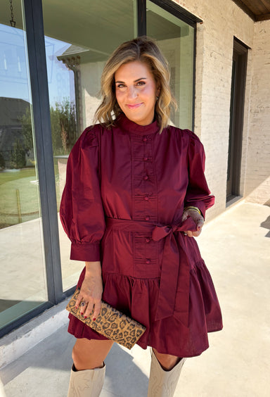 Rich burgundy makes this dress from Entro an easy favorite for all the plans filling up your fall calendar. The stand collar and split neckline create a classic look, while the button-front closure adds a pretty finishing detail. Long balloon sleeves bring soft volume to the silhouette and are finished with button cuffs for a more tailored touch. A removable self-tie belt lets you define the waist or switch up the look, while the tiered skirt adds movement and shape. 