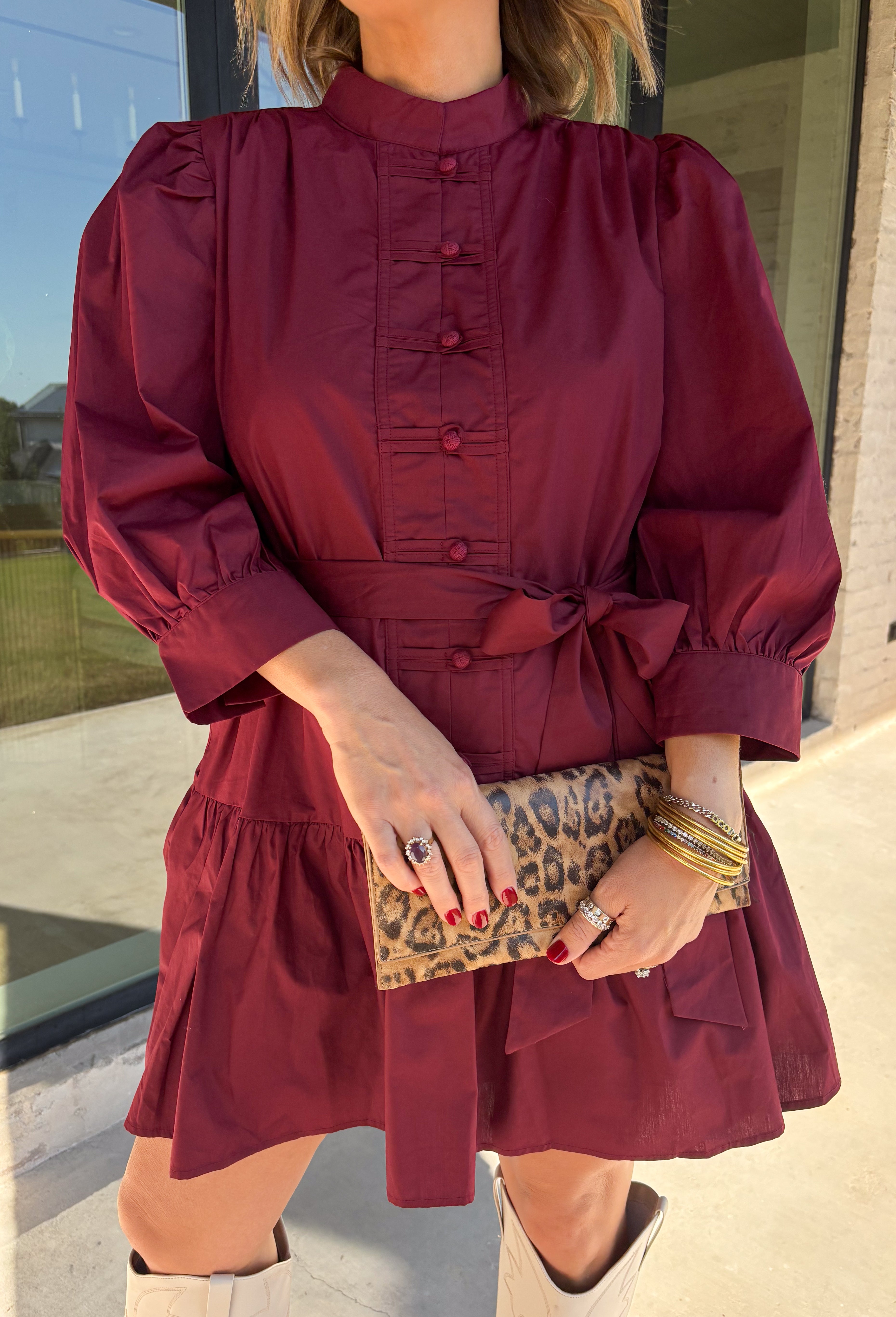 Rich burgundy makes this dress from Entro an easy favorite for all the plans filling up your fall calendar. The stand collar and split neckline create a classic look, while the button-front closure adds a pretty finishing detail. Long balloon sleeves bring soft volume to the silhouette and are finished with button cuffs for a more tailored touch. A removable self-tie belt lets you define the waist or switch up the look, while the tiered skirt adds movement and shape. 