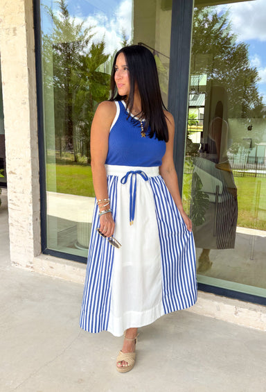 Sporty meets polished in this sleeveless midi dress by Entro—an effortless spring staple you’ll love wearing on repeat. The royal blue top features crisp white trim along the neckline and arm openings, while the white skirt is accented with royal blue and white stripe detailing along the sides for a clean, flattering look. An elastic tie waist adds comfort and shape, and side pockets make it as practical as it is cute. Fully lined and made from breathable cotton, this dress is perfect for all season long.